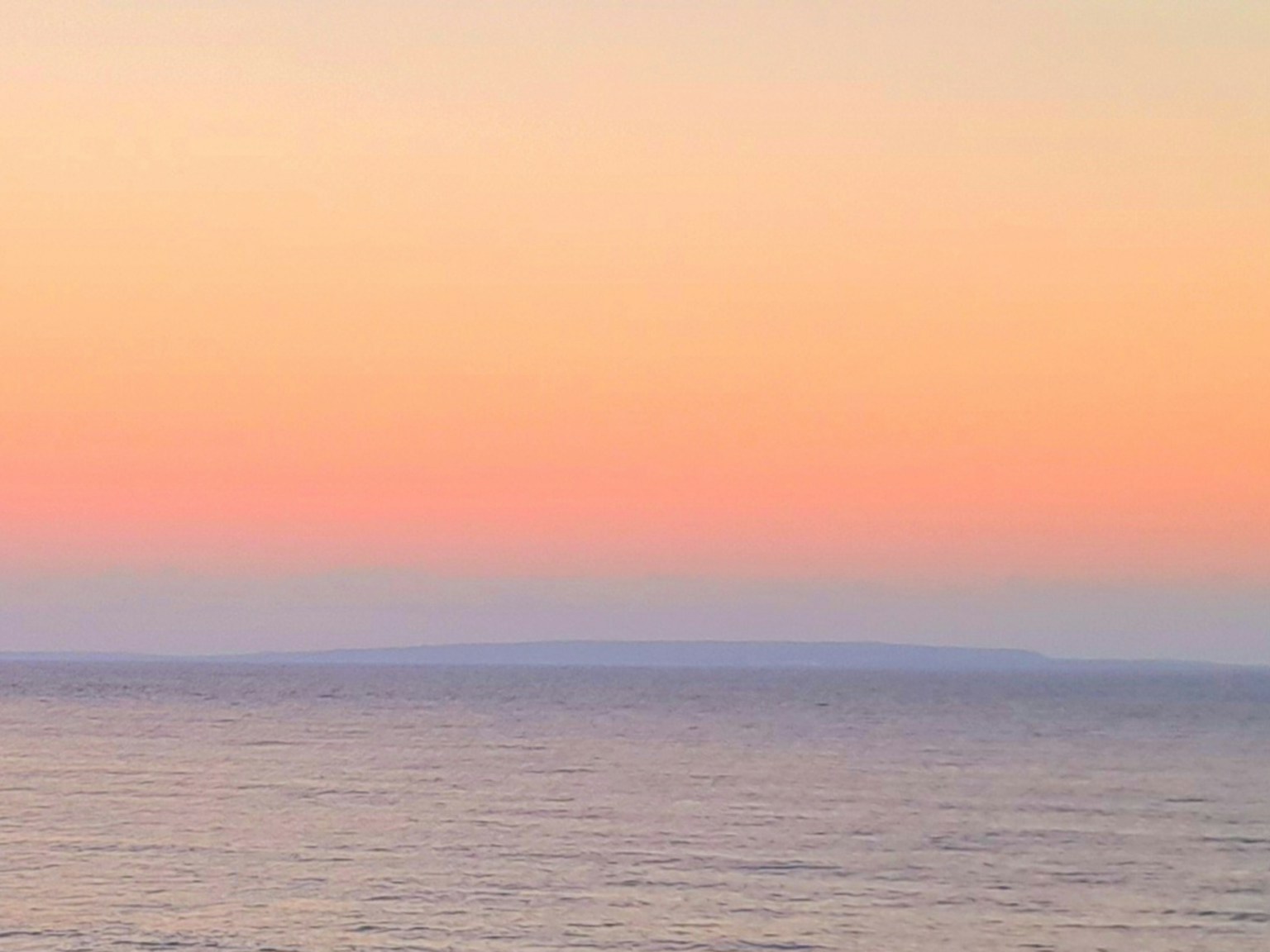 Ruhiges Meer mit einem sanften rosa Himmel