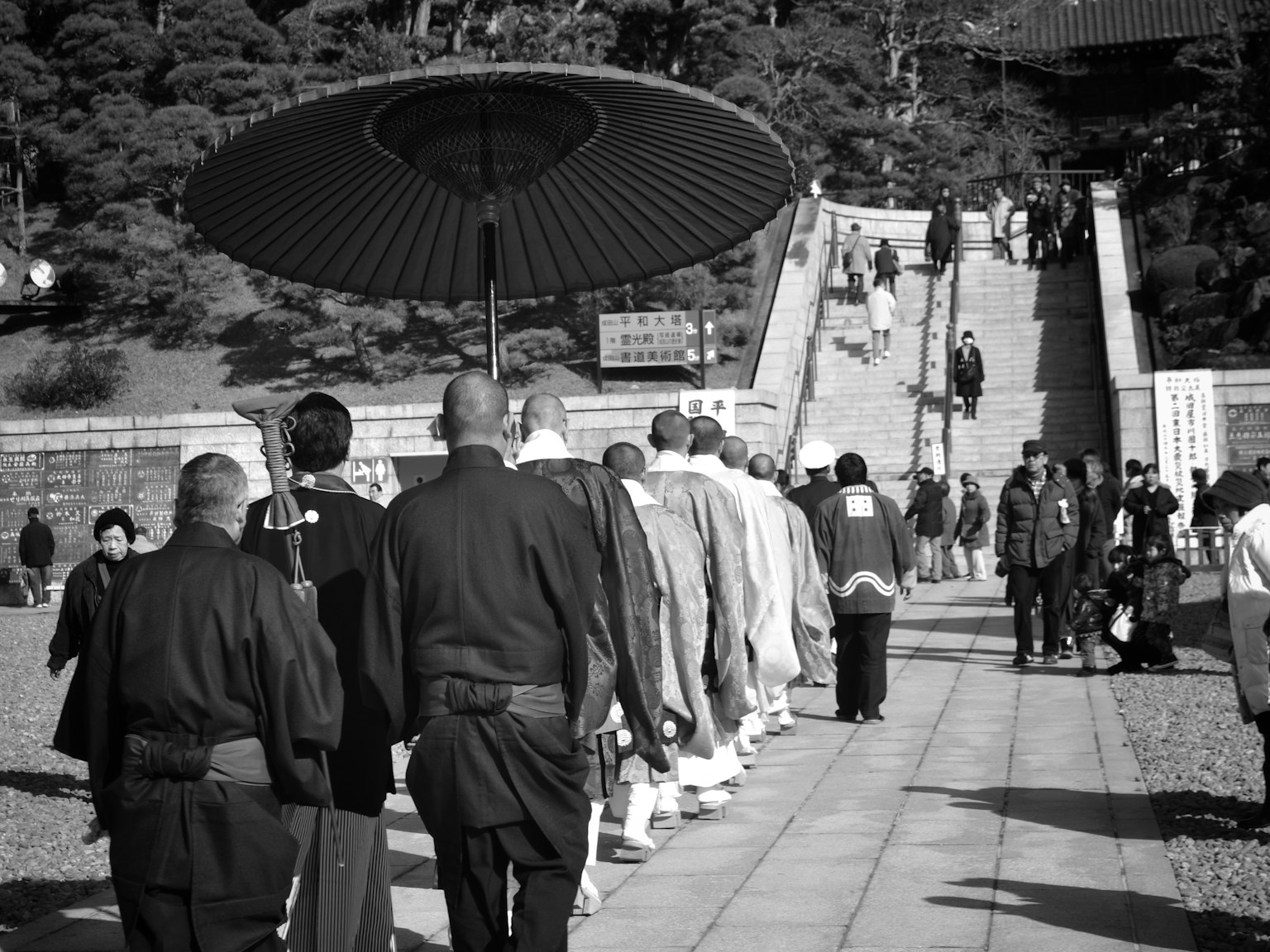 ภาพขาวดำของขบวนพระสงฆ์พร้อมกับบุคคลที่ถือร่ม