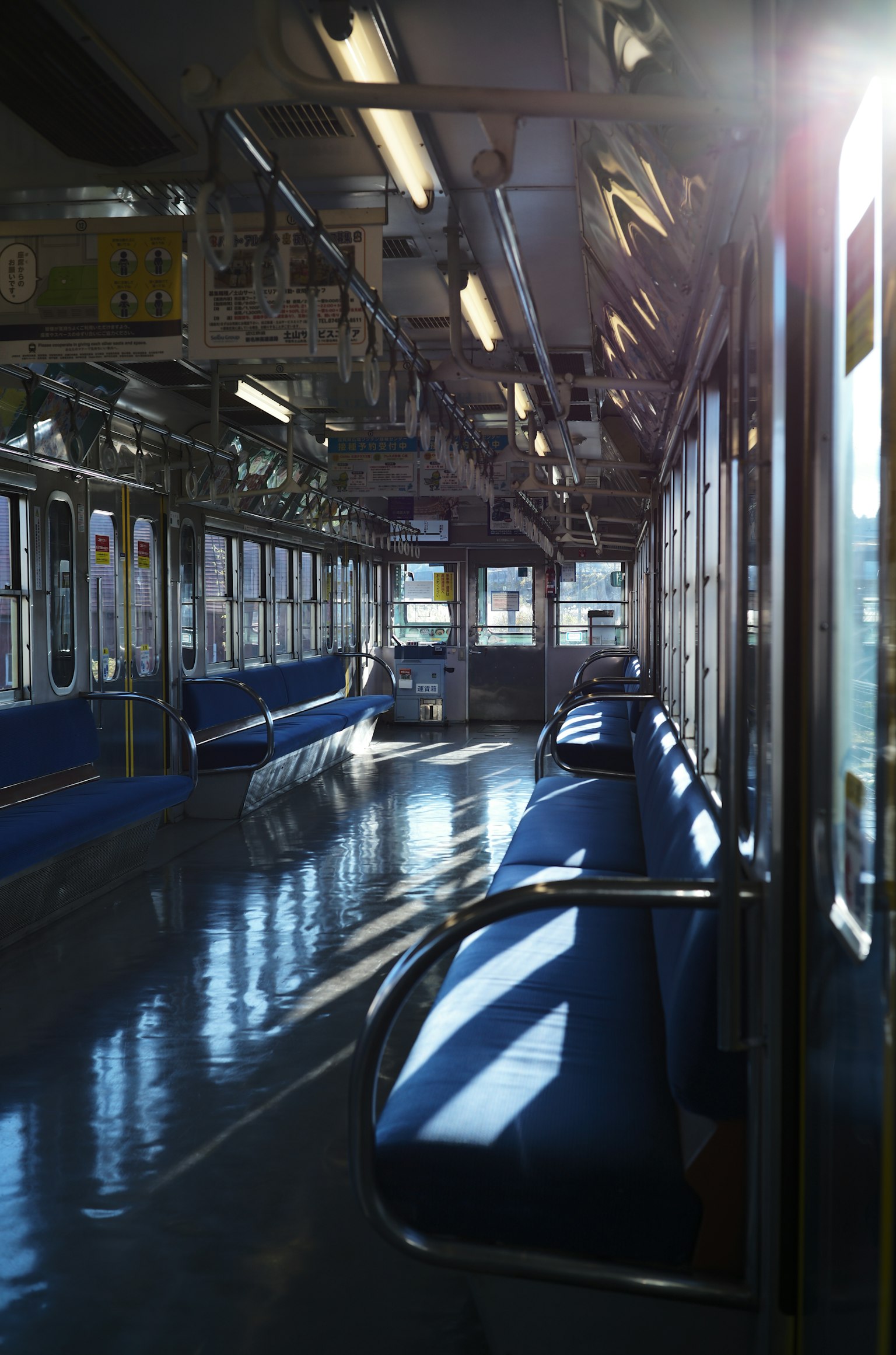 Wagon de train vide avec des bancs bleus et des reflets de lumière