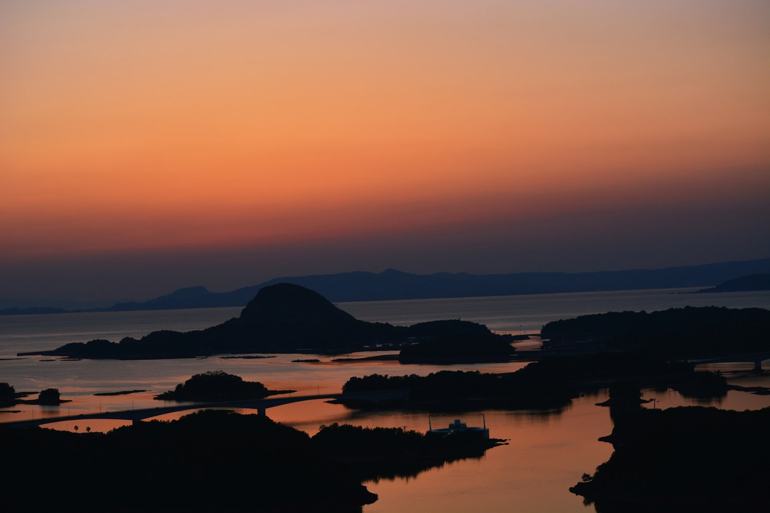 Coucher de soleil sur la mer avec des îles eau calme reflétant un dégradé d'orange et de bleu