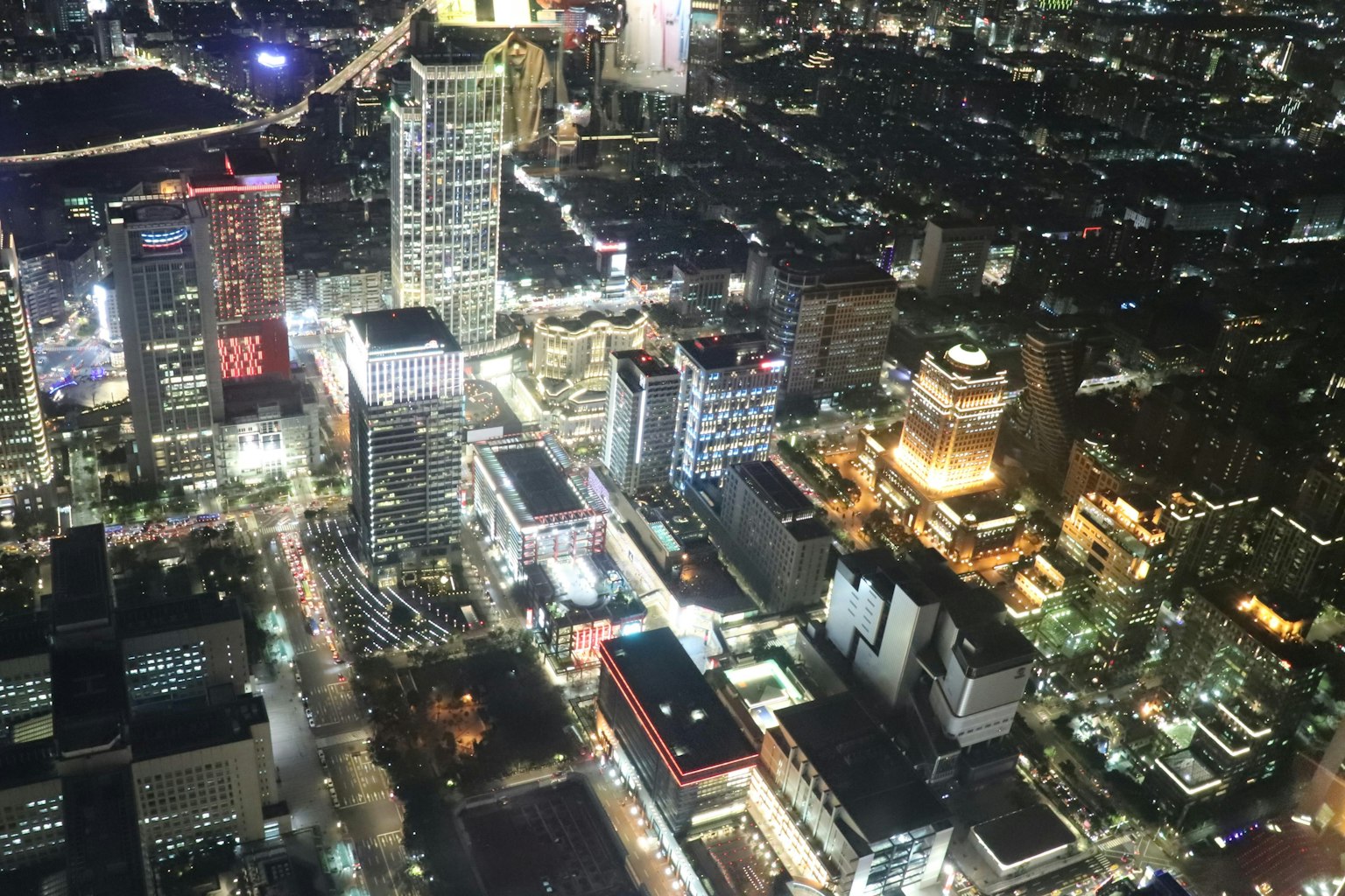 Luftaufnahme einer Stadt bei Nacht mit Hochhäusern und hellen Straßenlaternen