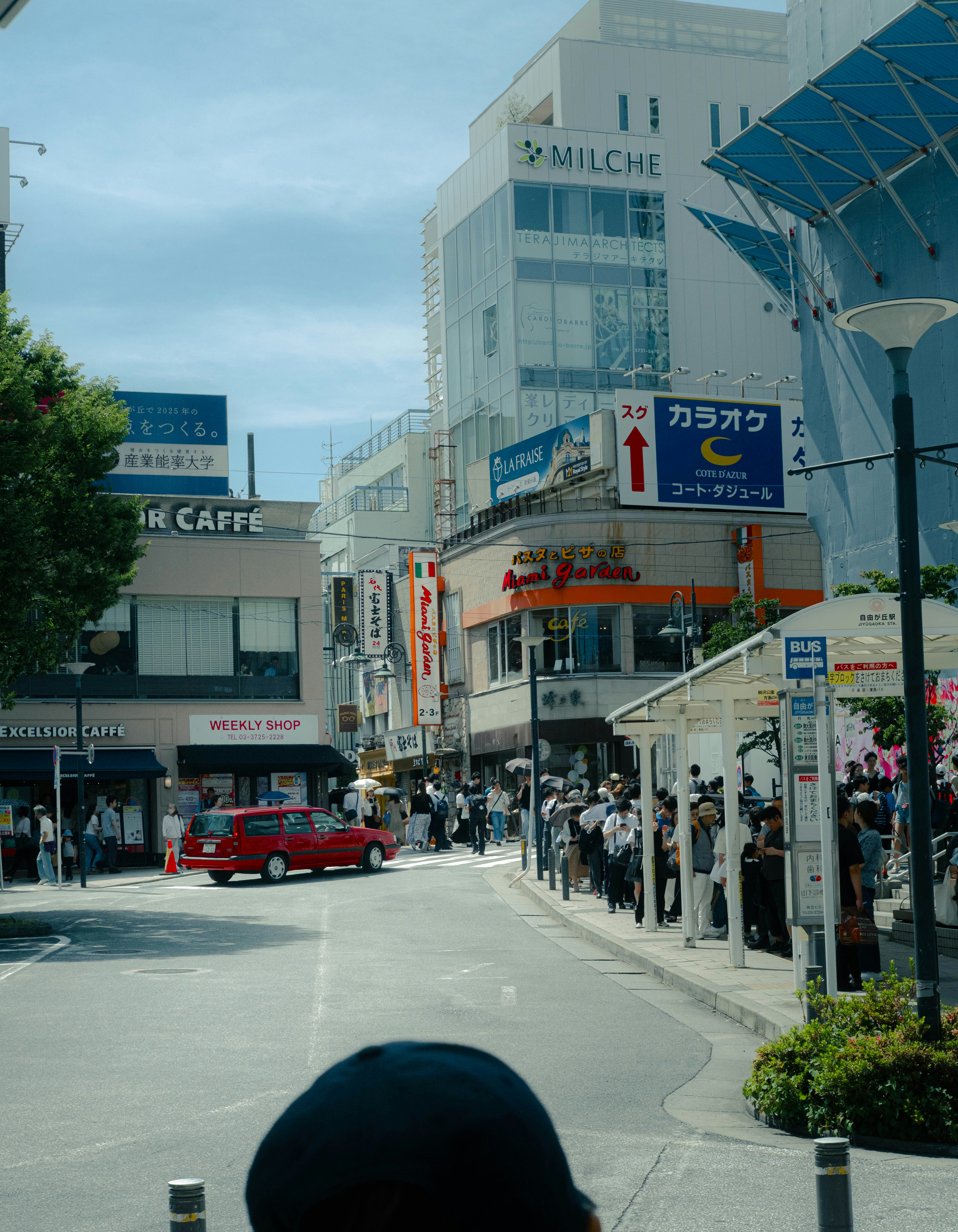 赤いクラシックカーが走る商店街の通り