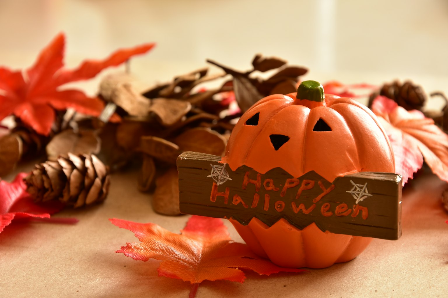 Citrouille orange décorative avec un panneau Joyeux Halloween entouré de feuilles d'automne