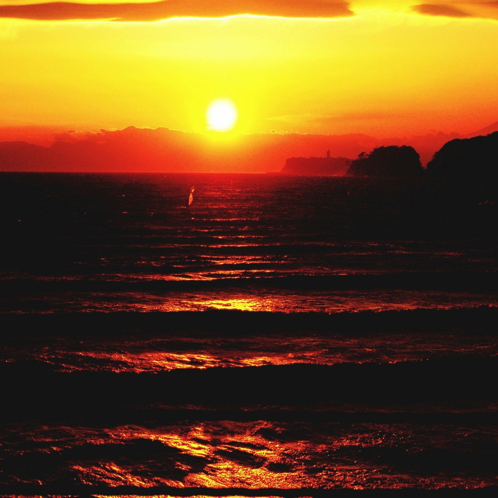 夕焼けの海に沈む太陽と波の反射