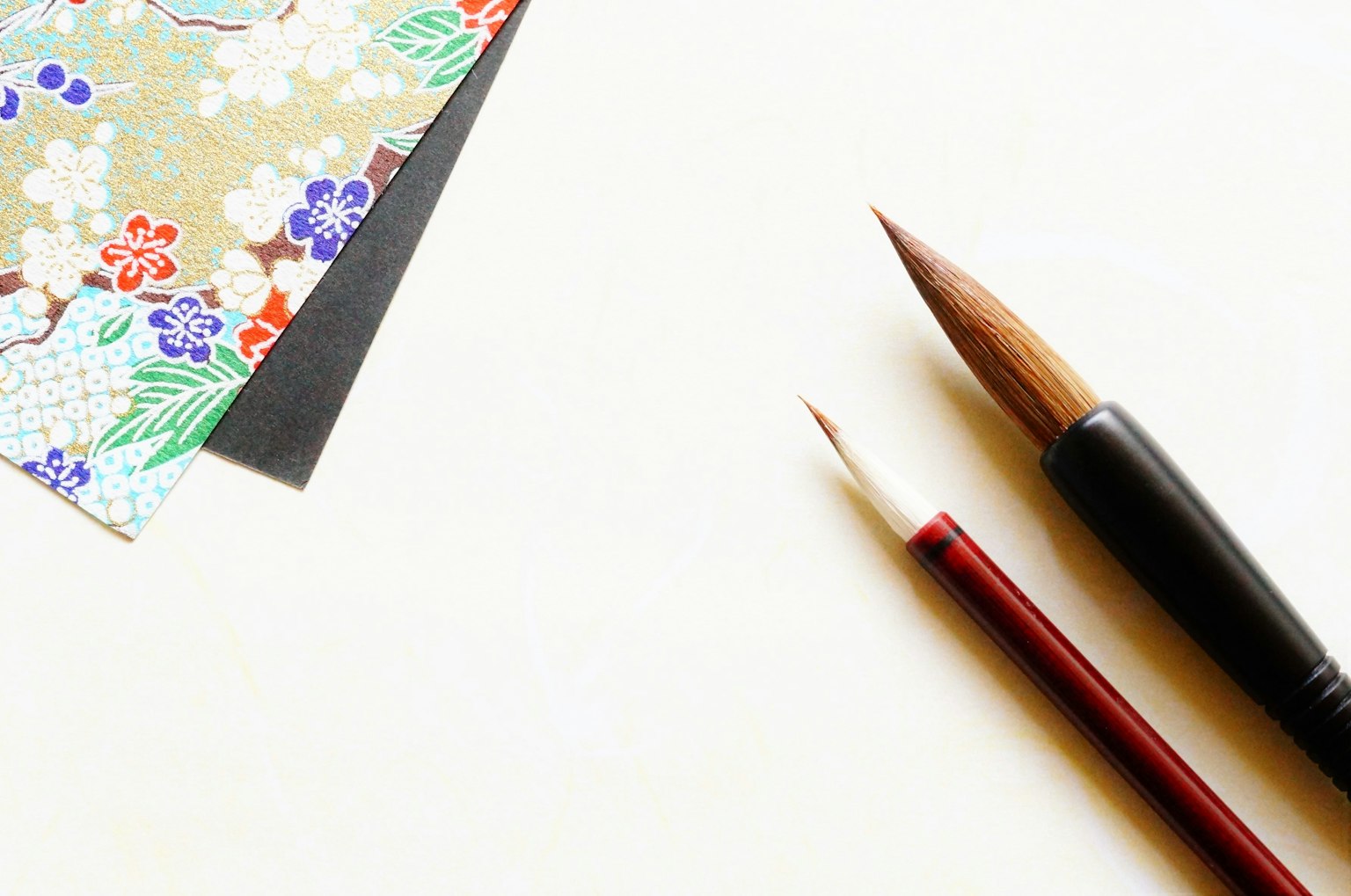 Bunt gemustertes Papier und zwei Pinsel in einer einfachen Anordnung