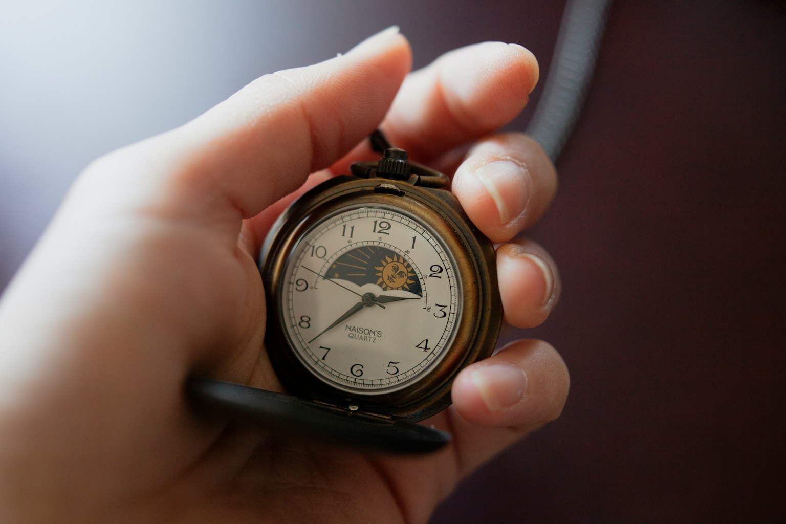 Un orologio da tasca classico tenuto in una mano con un design semplice