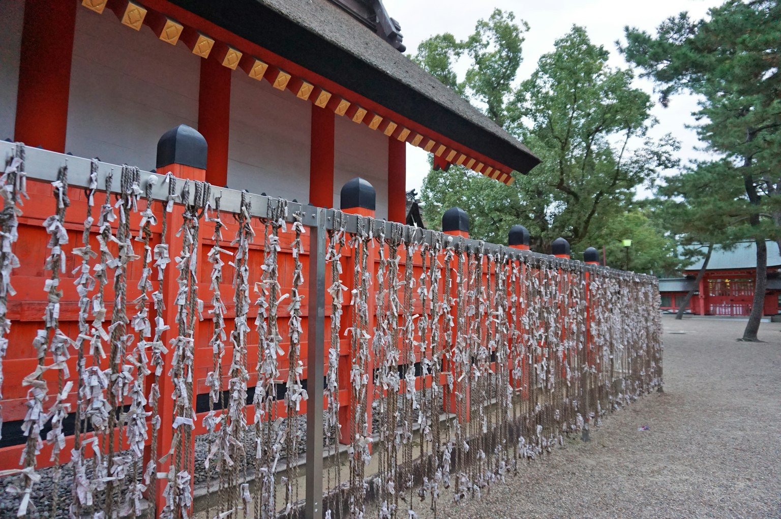 Vista de un santuario con paredes rojas y omikuji colgantes