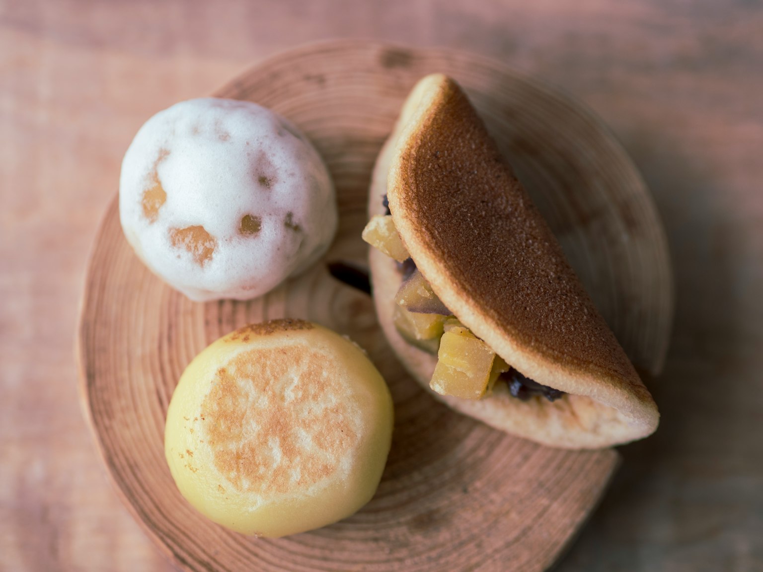 Paduan makanan penutup di atas piring kayu dengan roti isi buah dan dua permen bulat