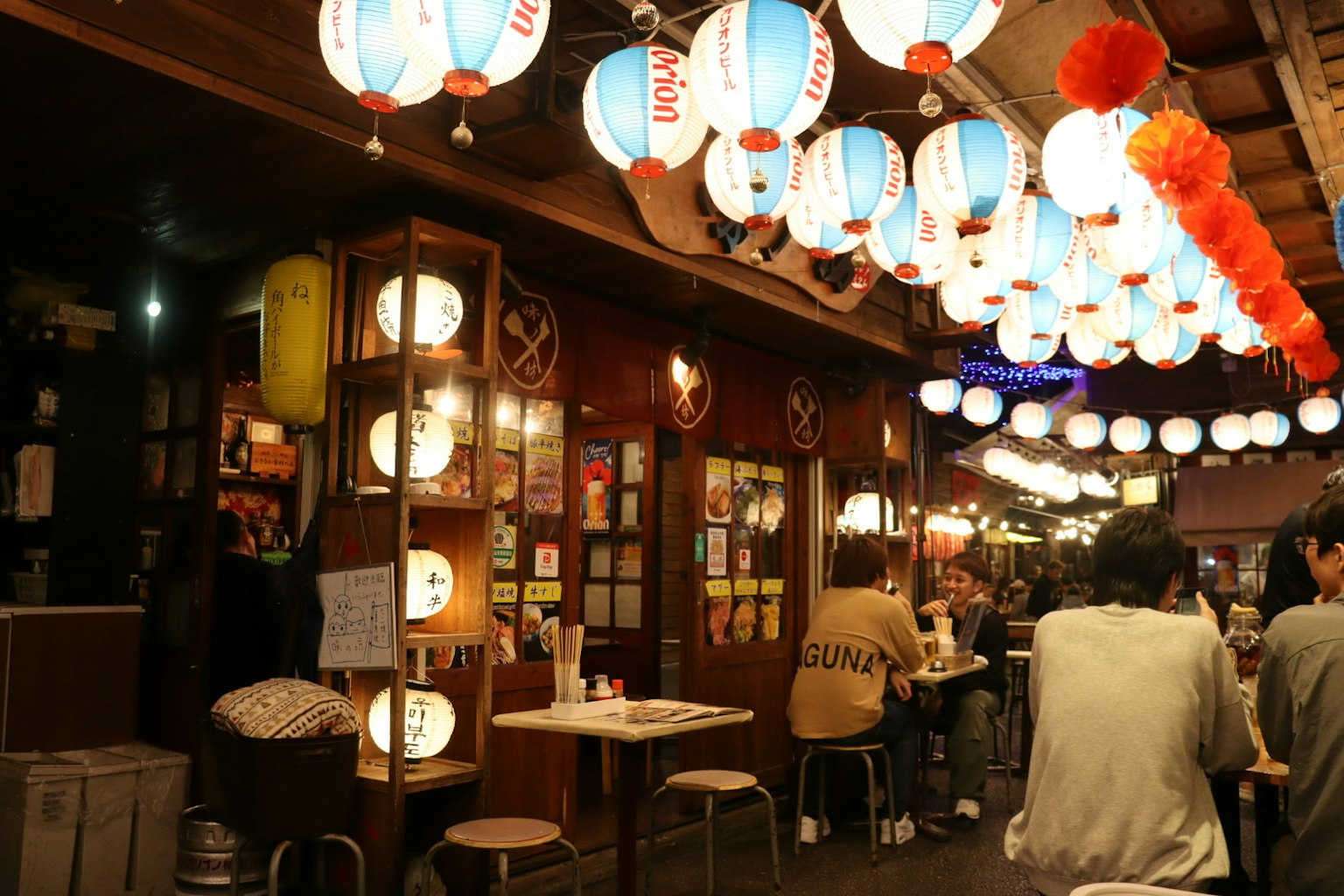 Interno di izakaya vivace con lanterne colorate e tavoli