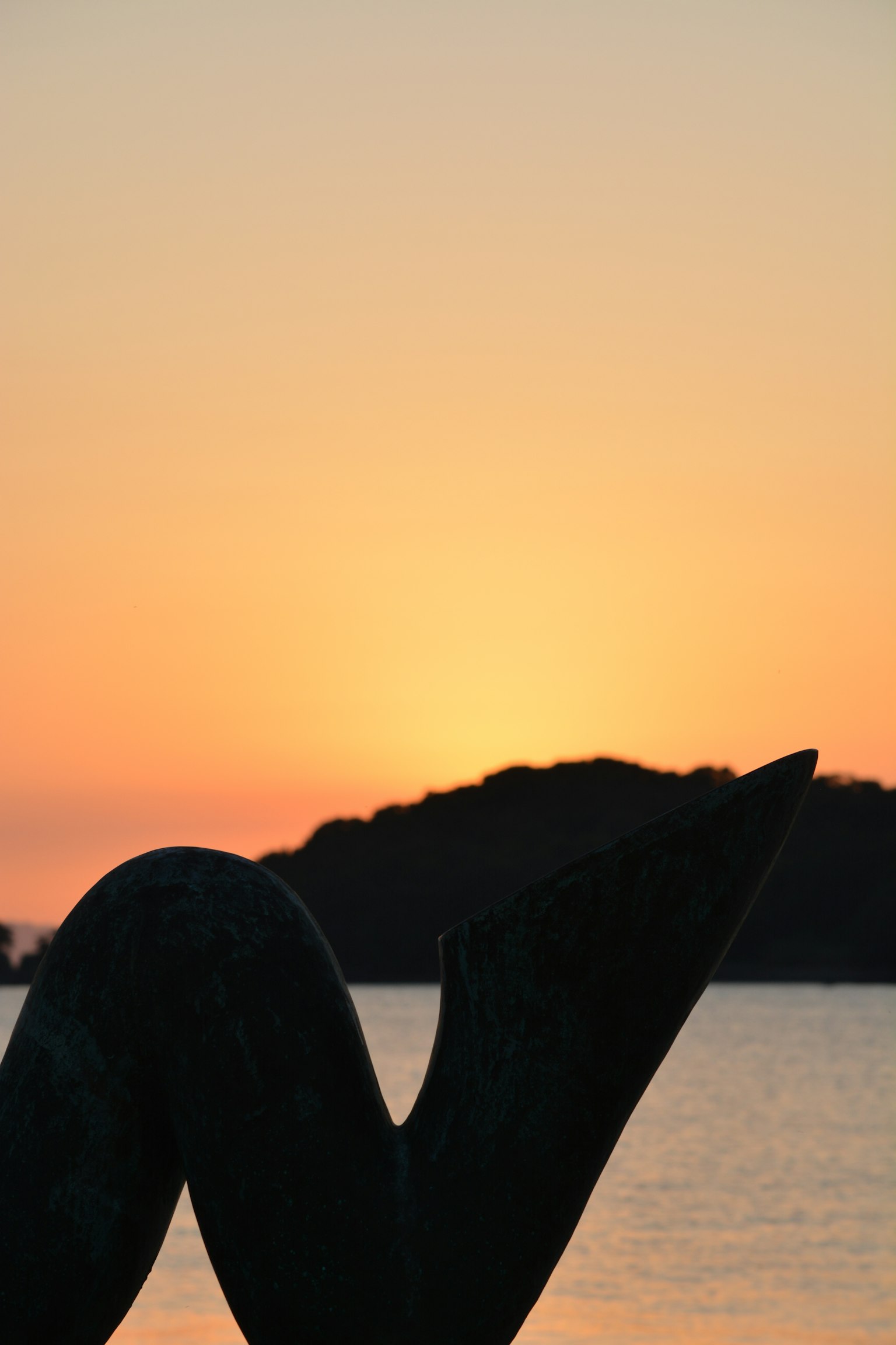 Silhouette di una scultura contro un tramonto