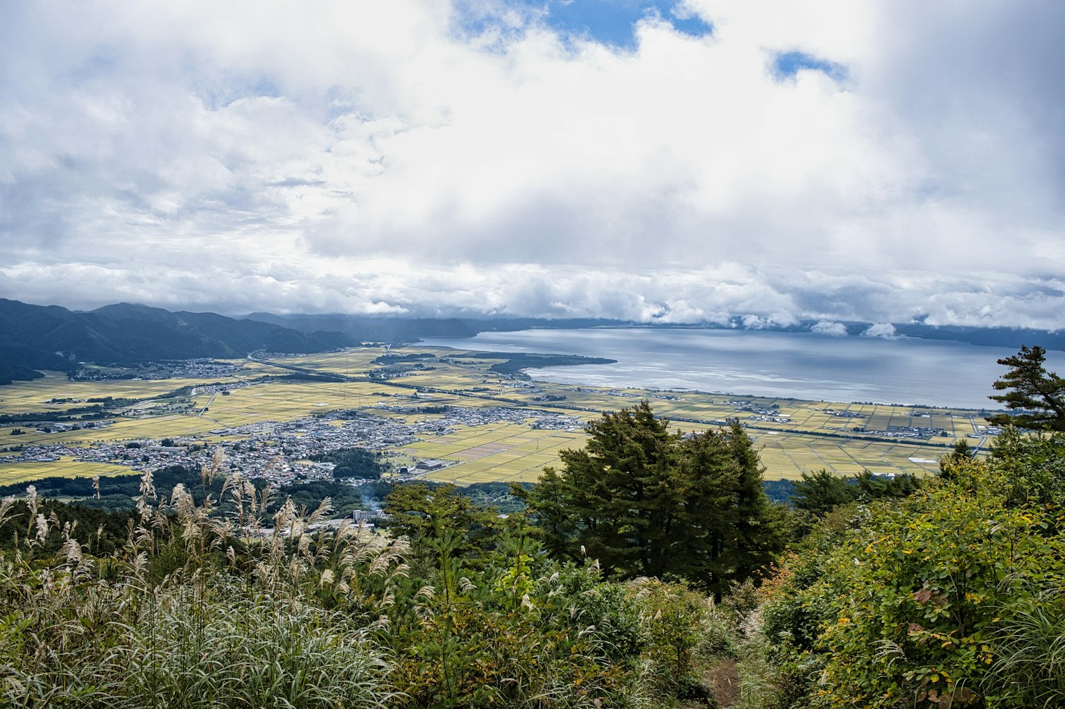 Une vue panoramique sur les montagnes et un lac avec un ciel bleu et des nuages épars