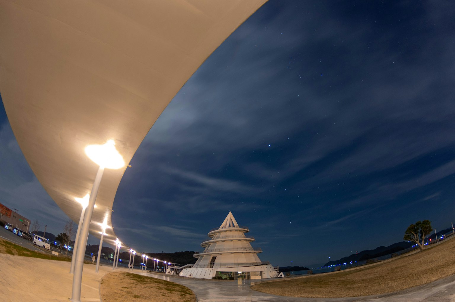 Bâtiment en forme de pyramide illuminé la nuit sous un ciel nuageux