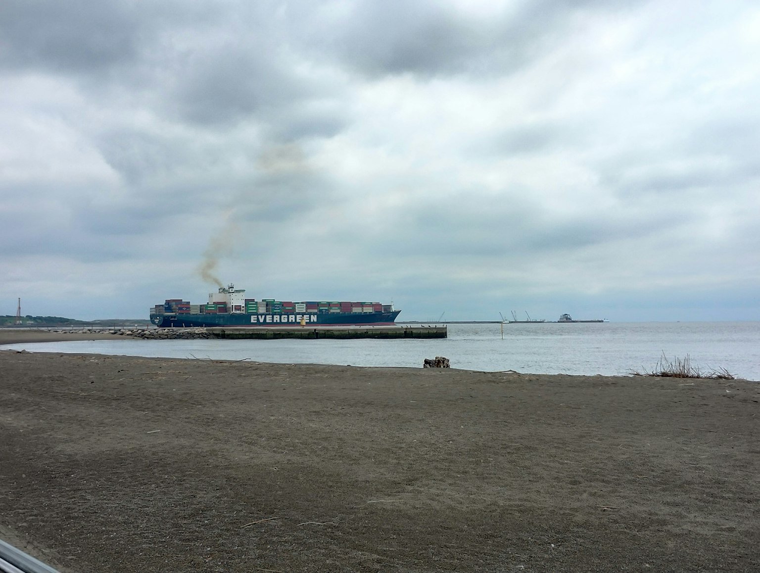 Barco de carga atracado cerca de la costa bajo un cielo nublado