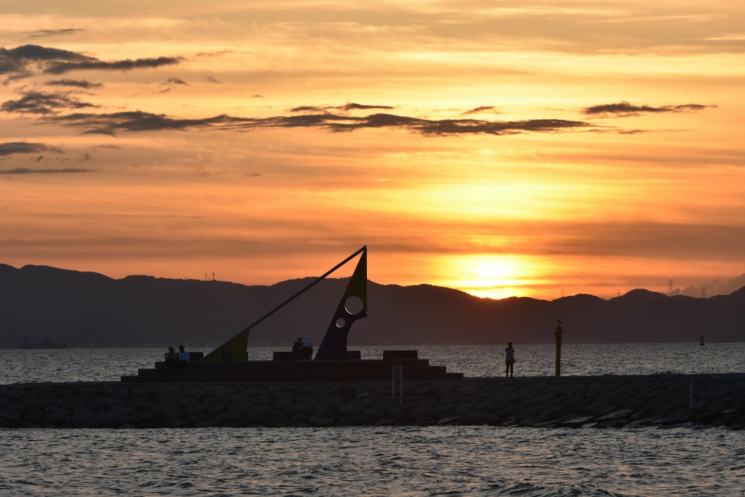 Silhouette di una struttura con un grande orologio contro un tramonto sul mare