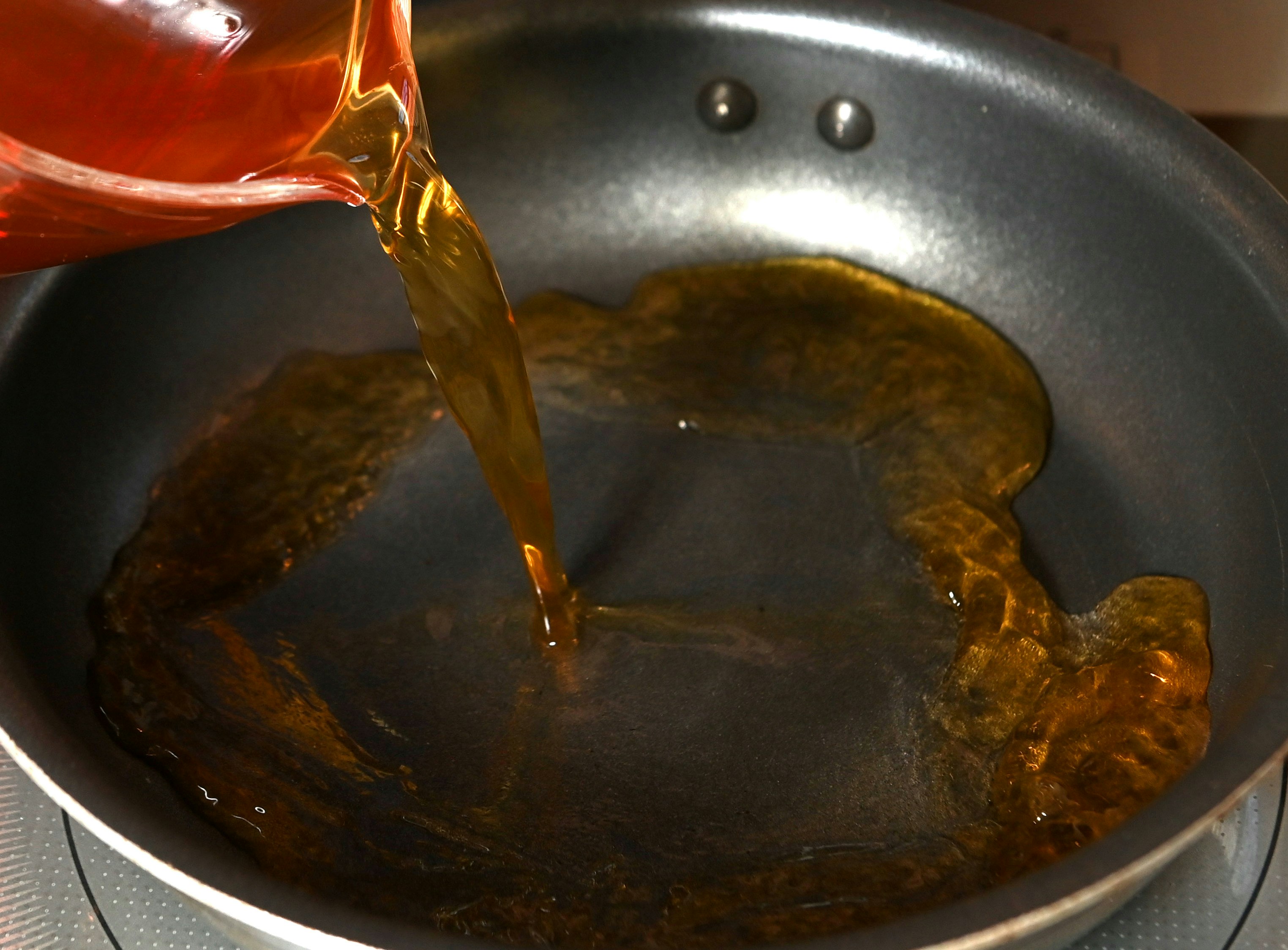 フライパンで煮込む茶色いソースに注ぐ液体