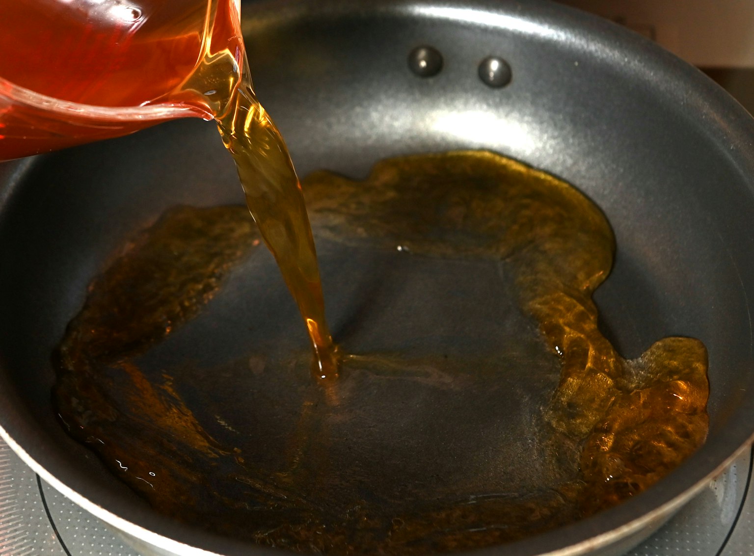 Versare olio in una padella con un ricco colore dorato preparando per cucinare