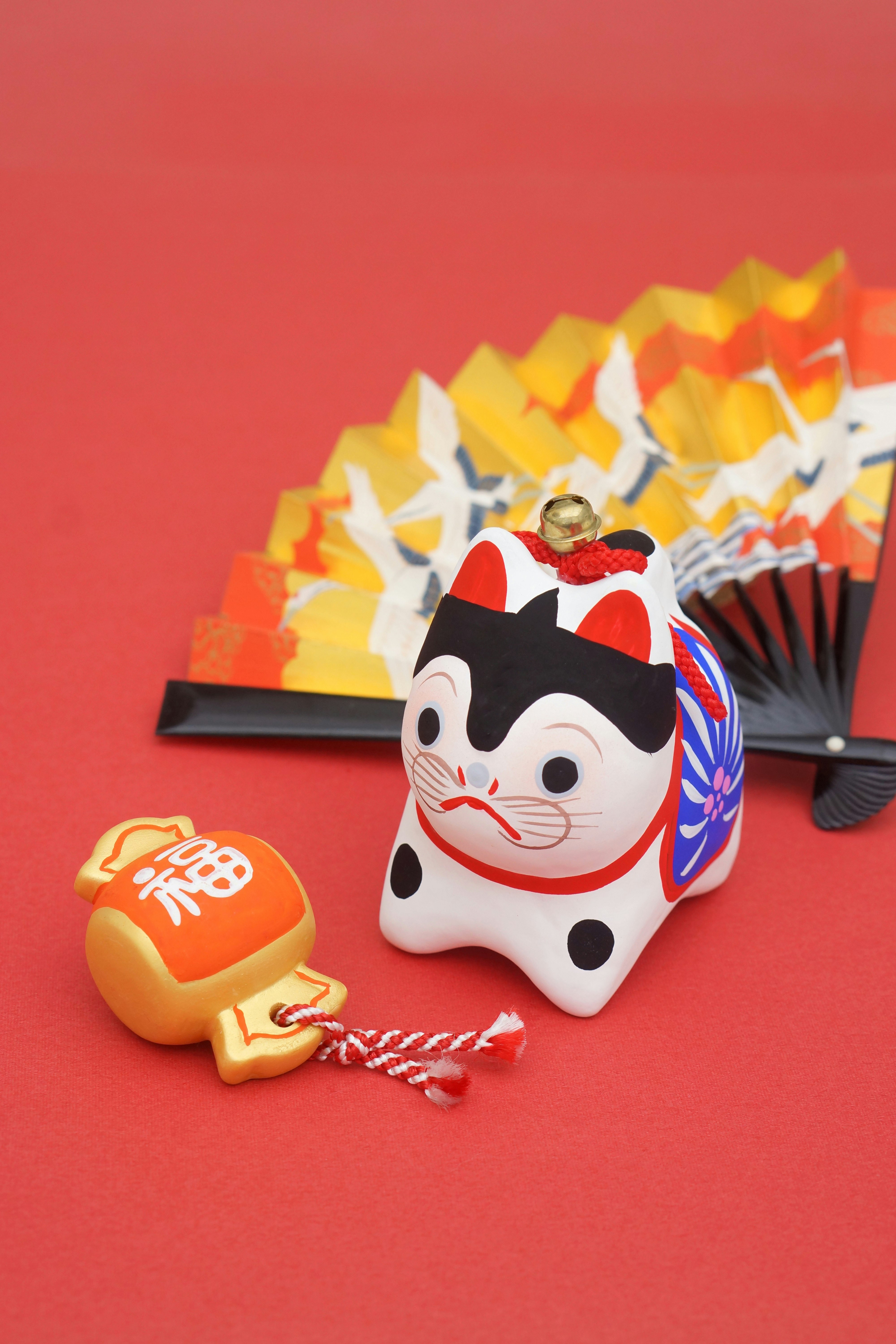 Portafortuna stile maneki-neko con piccoli oggetti su sfondo rosso