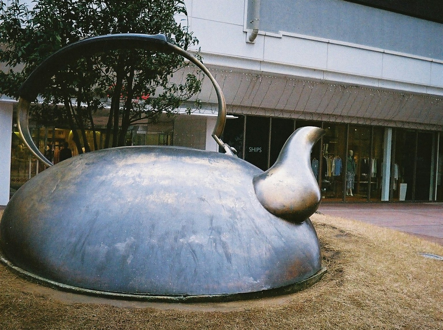 Grande sculpture en métal en forme de théière exposée à l'extérieur