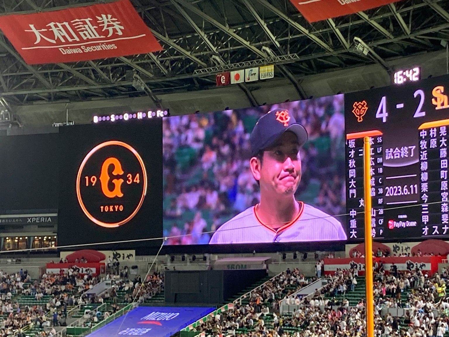 Ein Baseballspieler auf einem großen Bildschirm in einem Stadion mit dem Punktestand 4-2