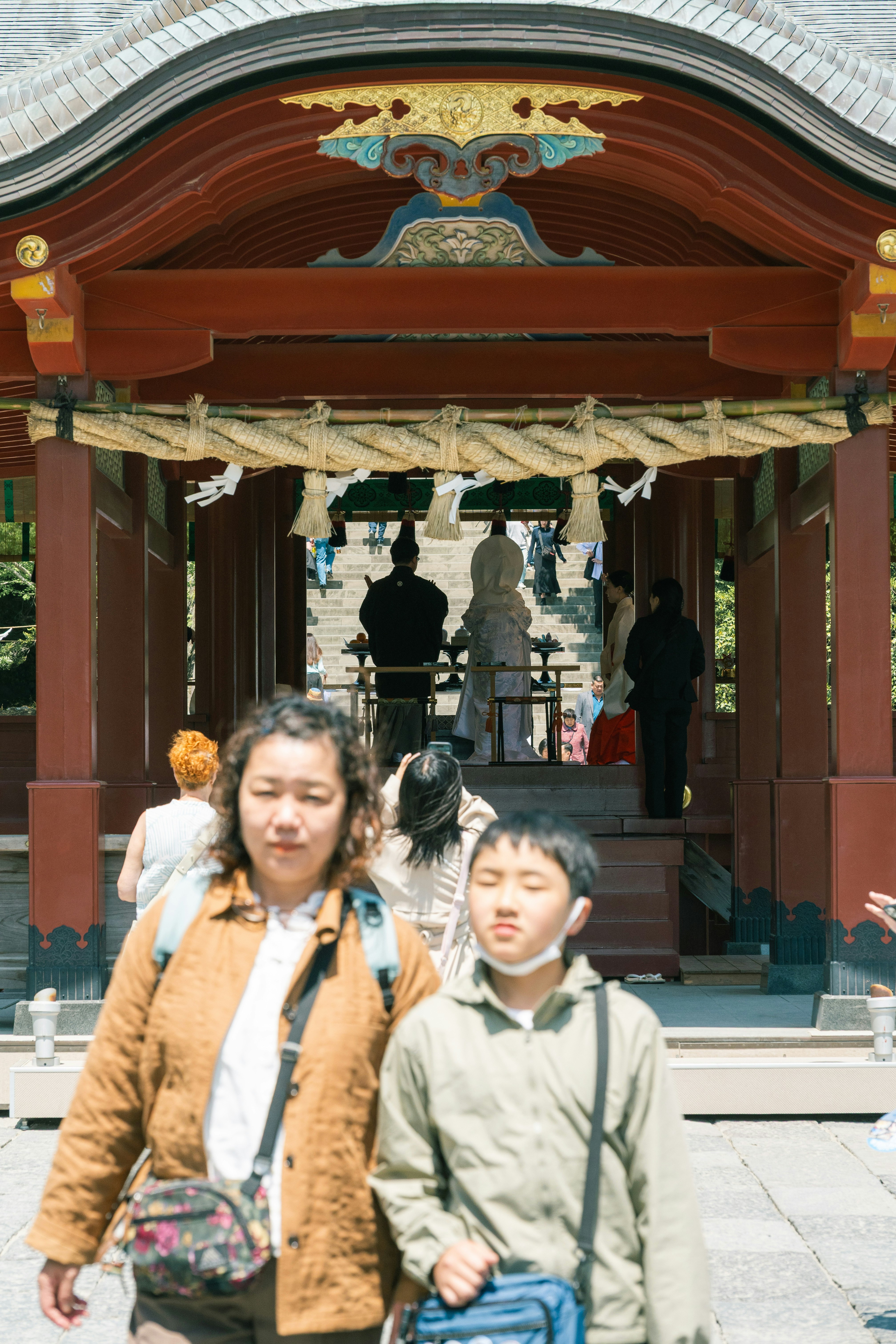 神社の社殿前で手をつなぐ親子