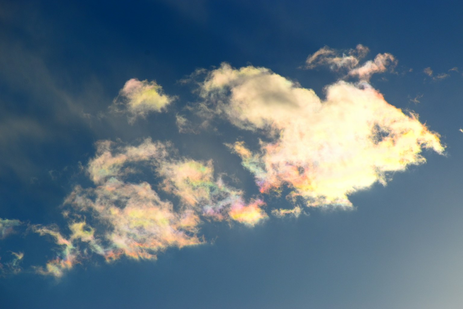 Irideszente Wolke, die in einem blauen Himmel schwebt