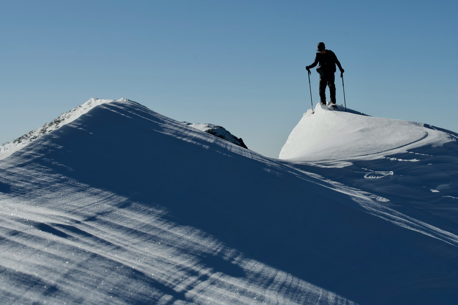 Orang berdiri di puncak gunung bersalju memegang tongkat ski