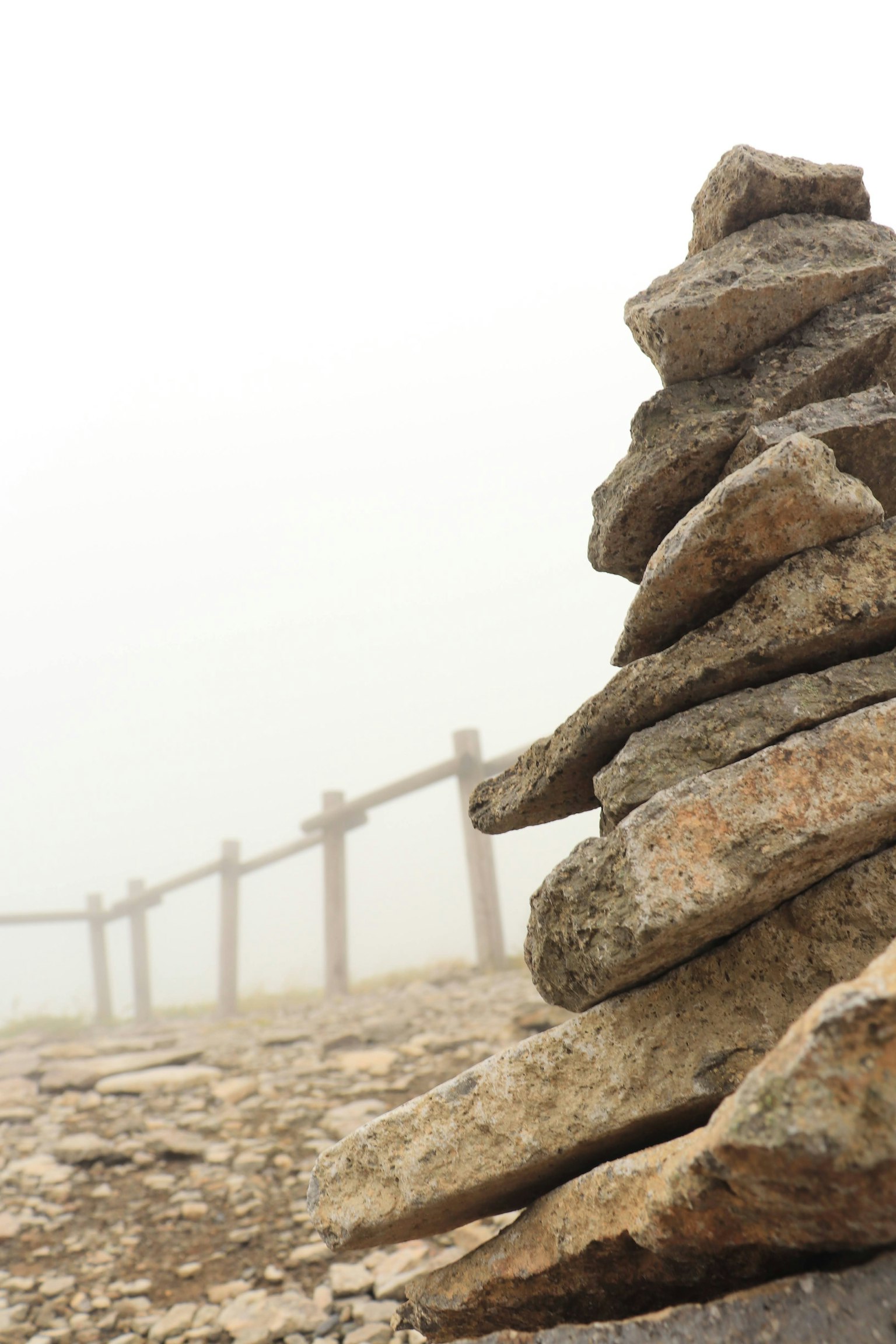 Mucchio di pietre nella nebbia con recinzione in legno sullo sfondo