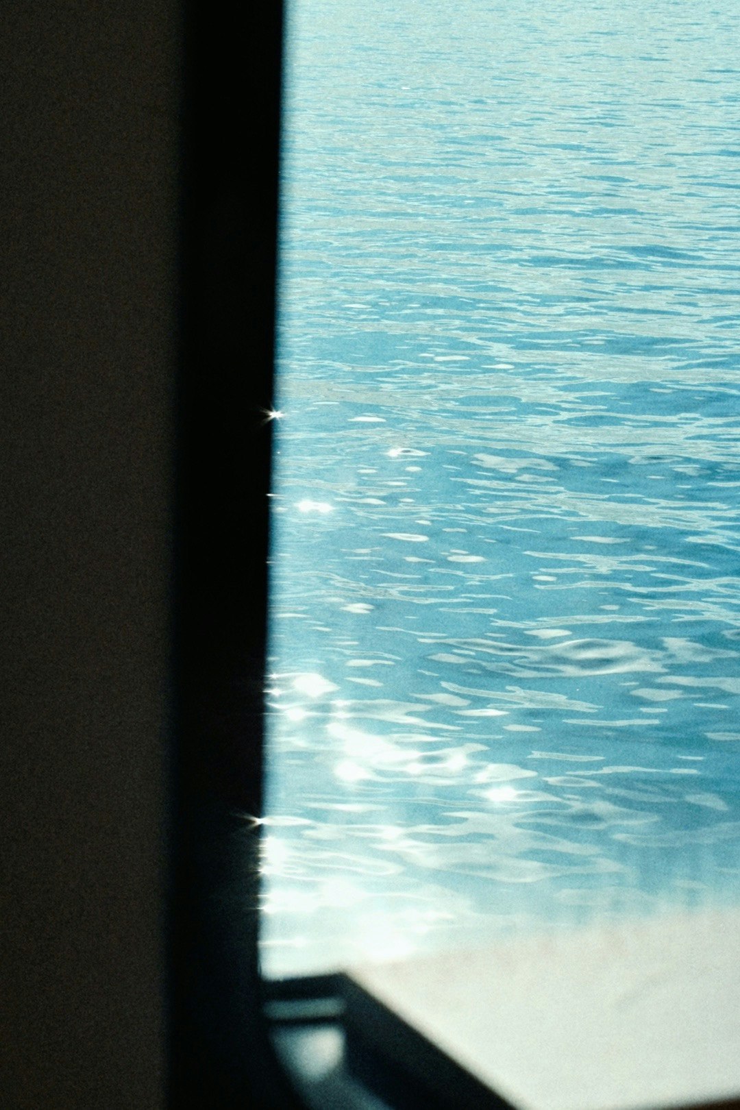 夏の青い海のきらめきが窓越しに見える景色
