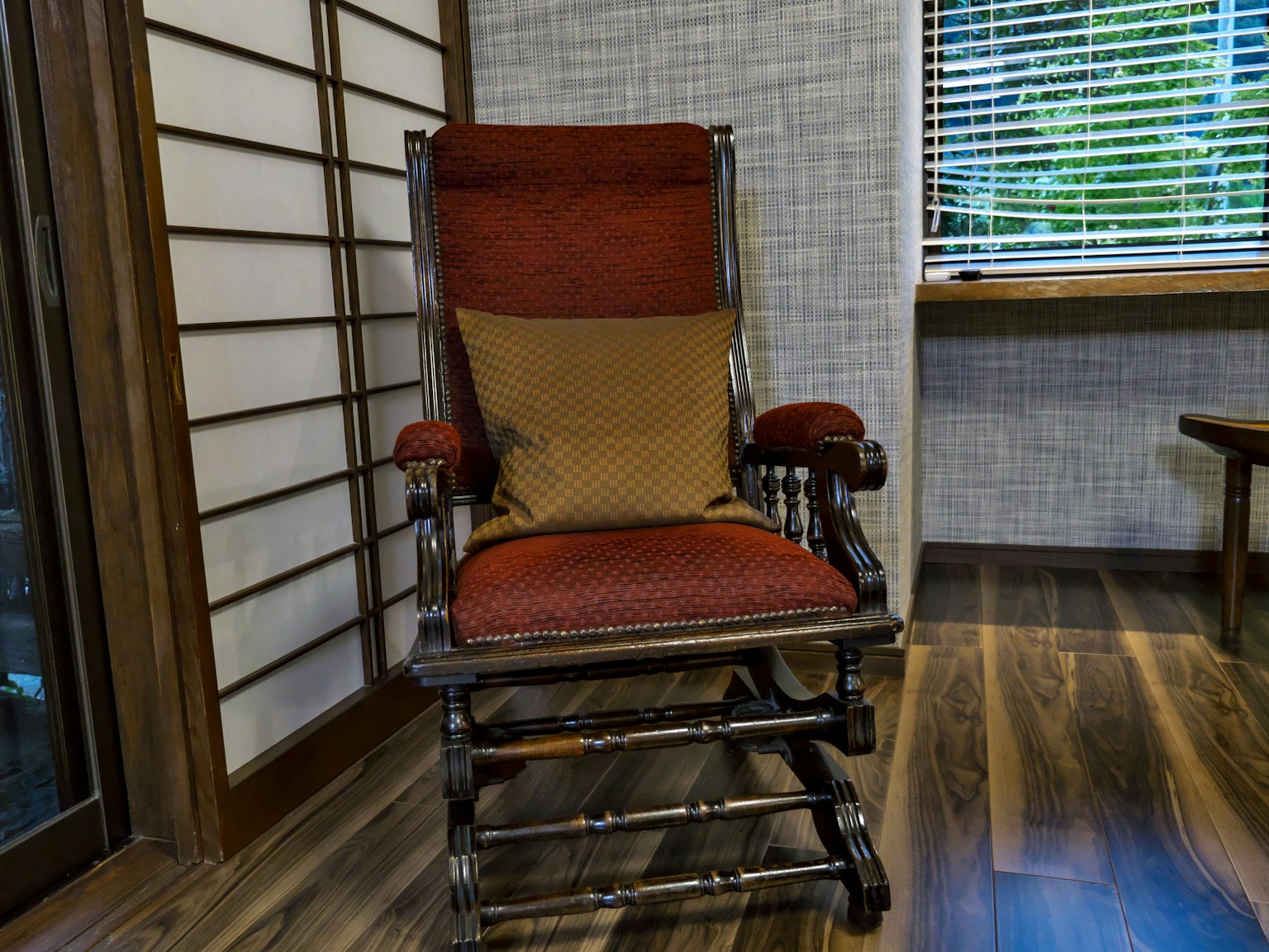 A rocking chair with a red cushion placed in a Japanese-style room