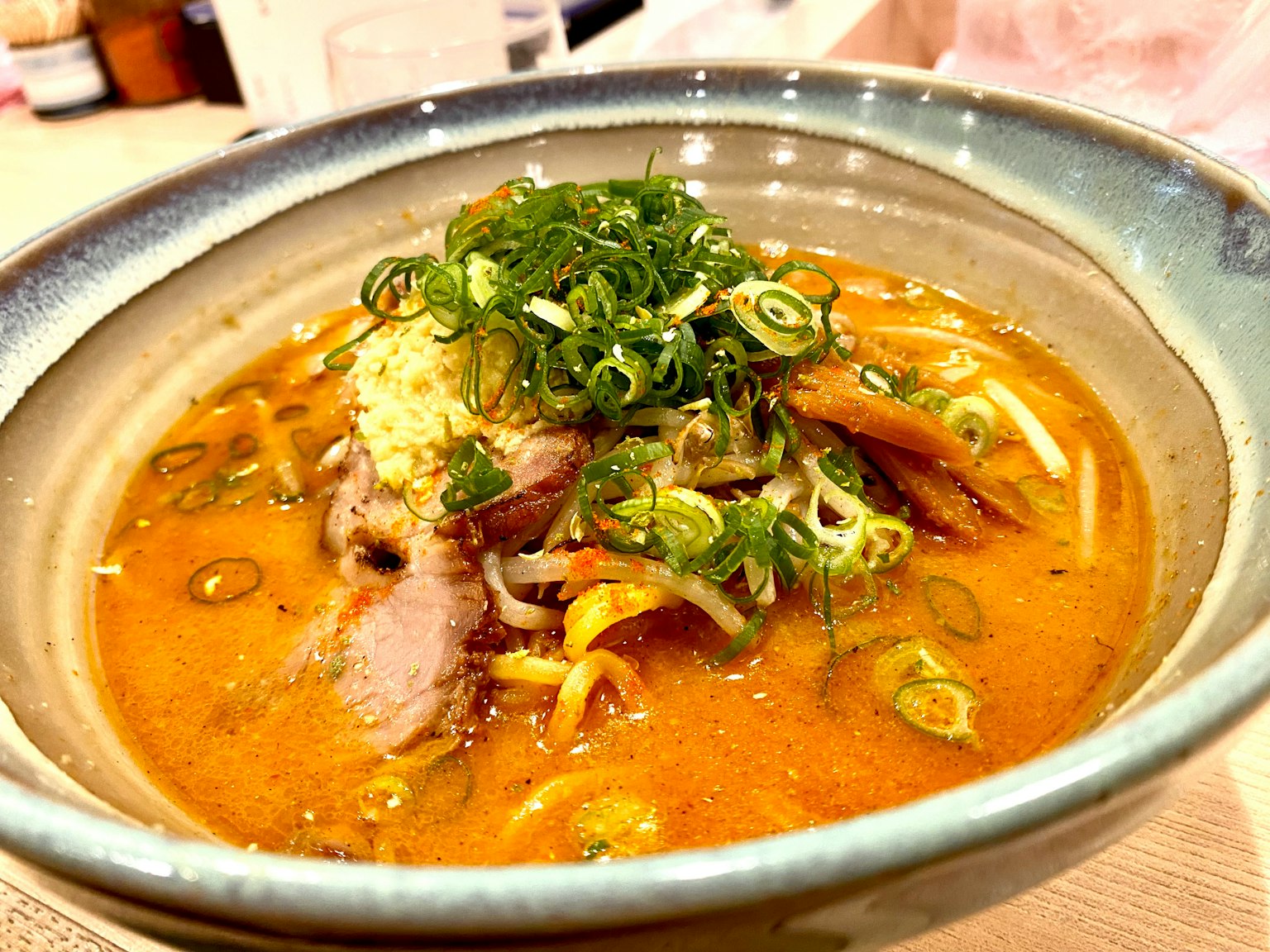 Una ciotola di ramen con cipollotti e fette di chashu in un brodo saporito