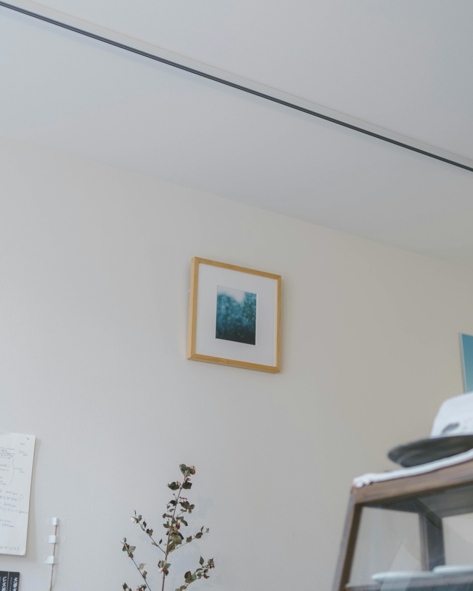 Une peinture de paysage bleu encadrée sur un mur blanc avec une décoration minimale