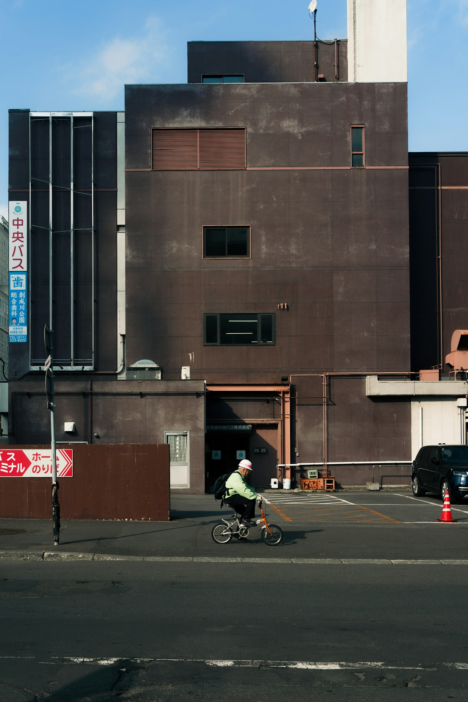Urban scene featuring a person on a bicycle against a modern building