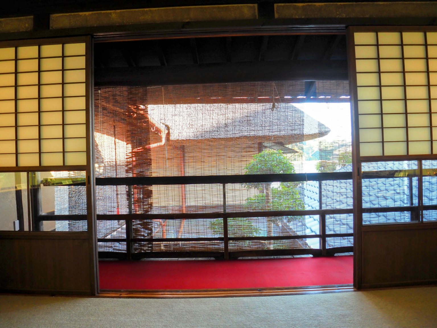 Pemandangan melalui pintu tradisional Jepang dengan layar shoji dan karpet merah