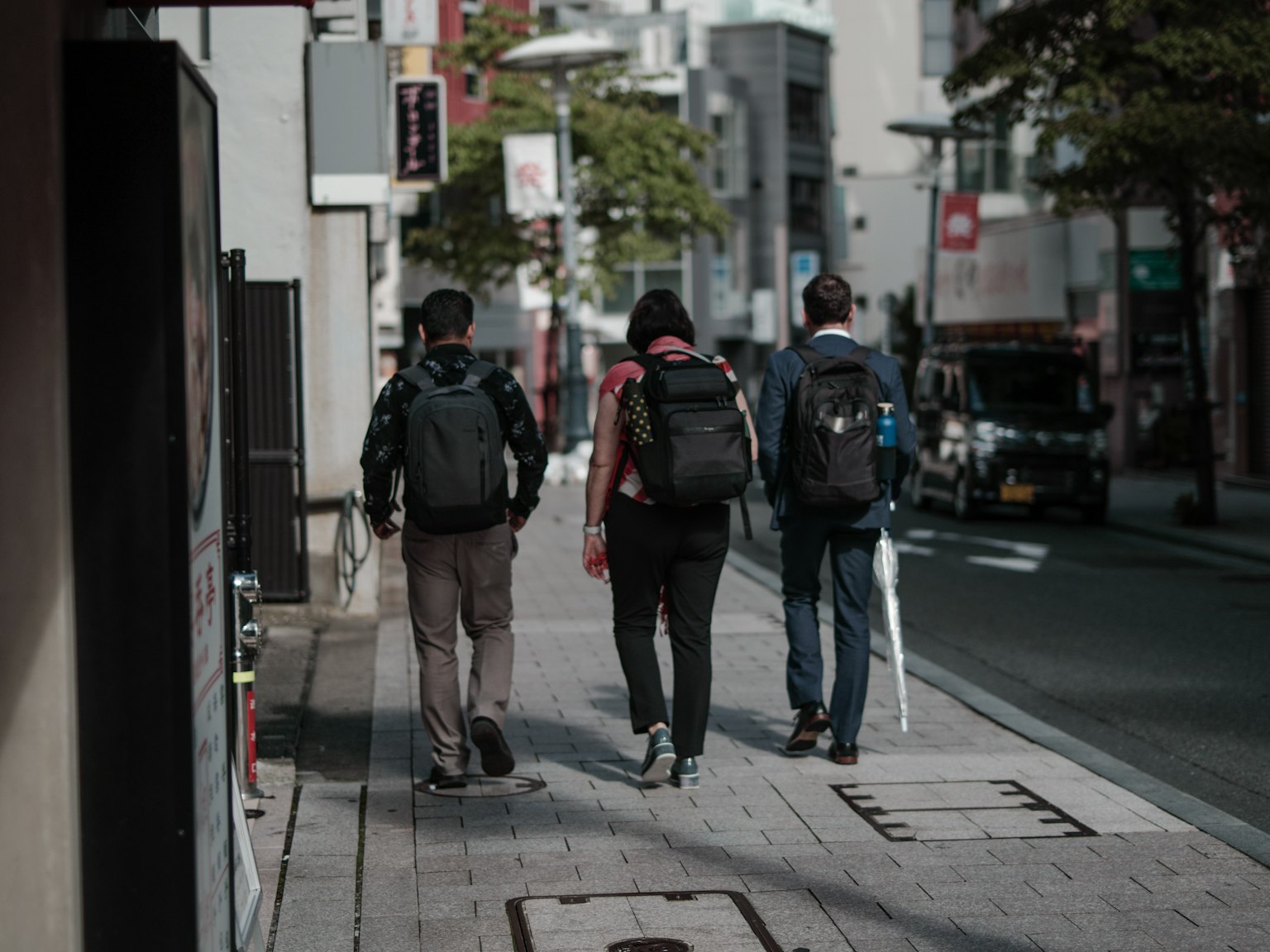 三个人背着背包在街上走