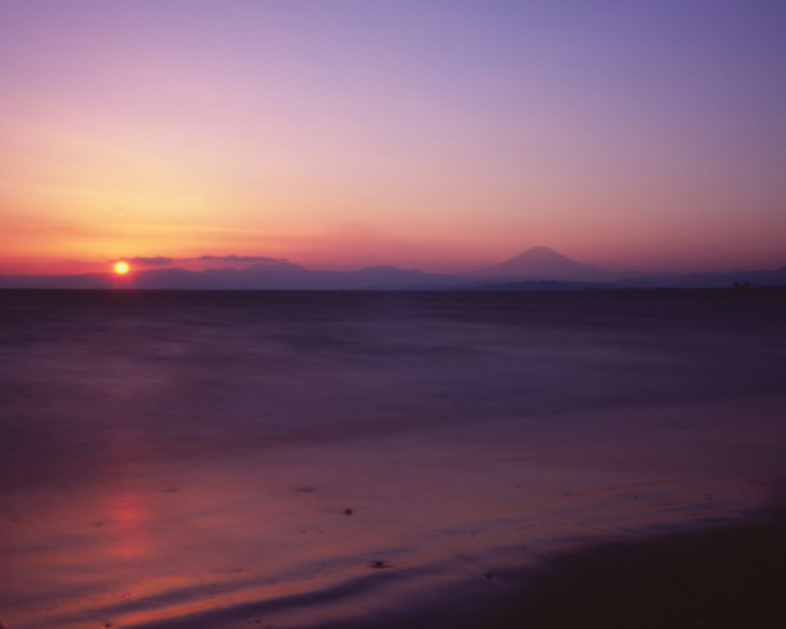 海面上日落的美麗風景與山的輪廓