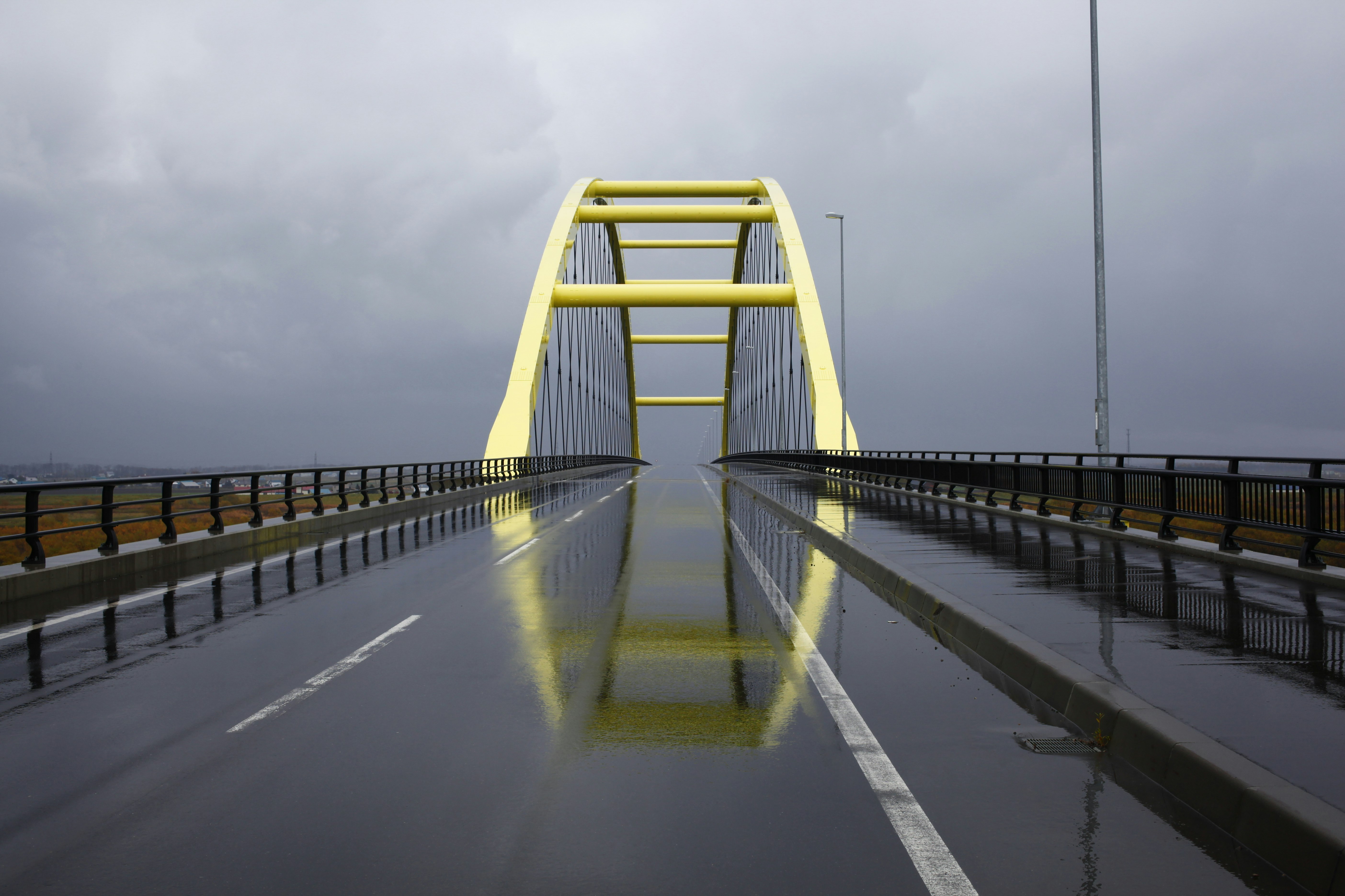 雨の高速道路を走る黄色い橋の支柱のある道路の先の眺め