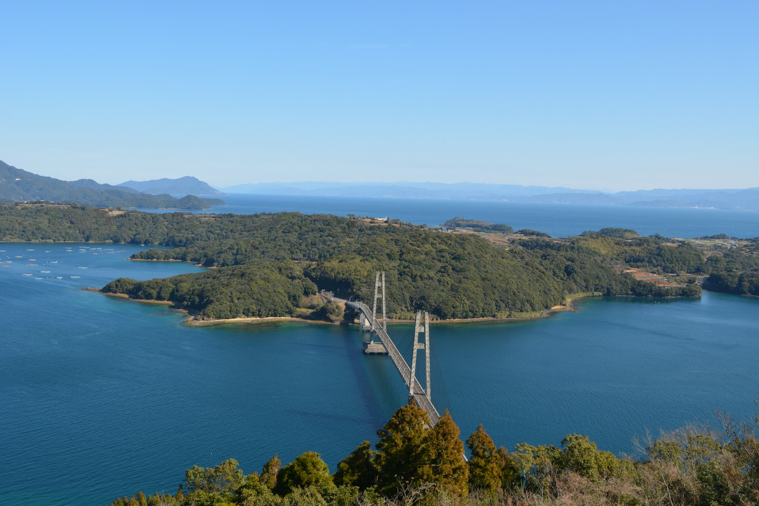 Scenic view of a bridge over blue water surrounded by green islands