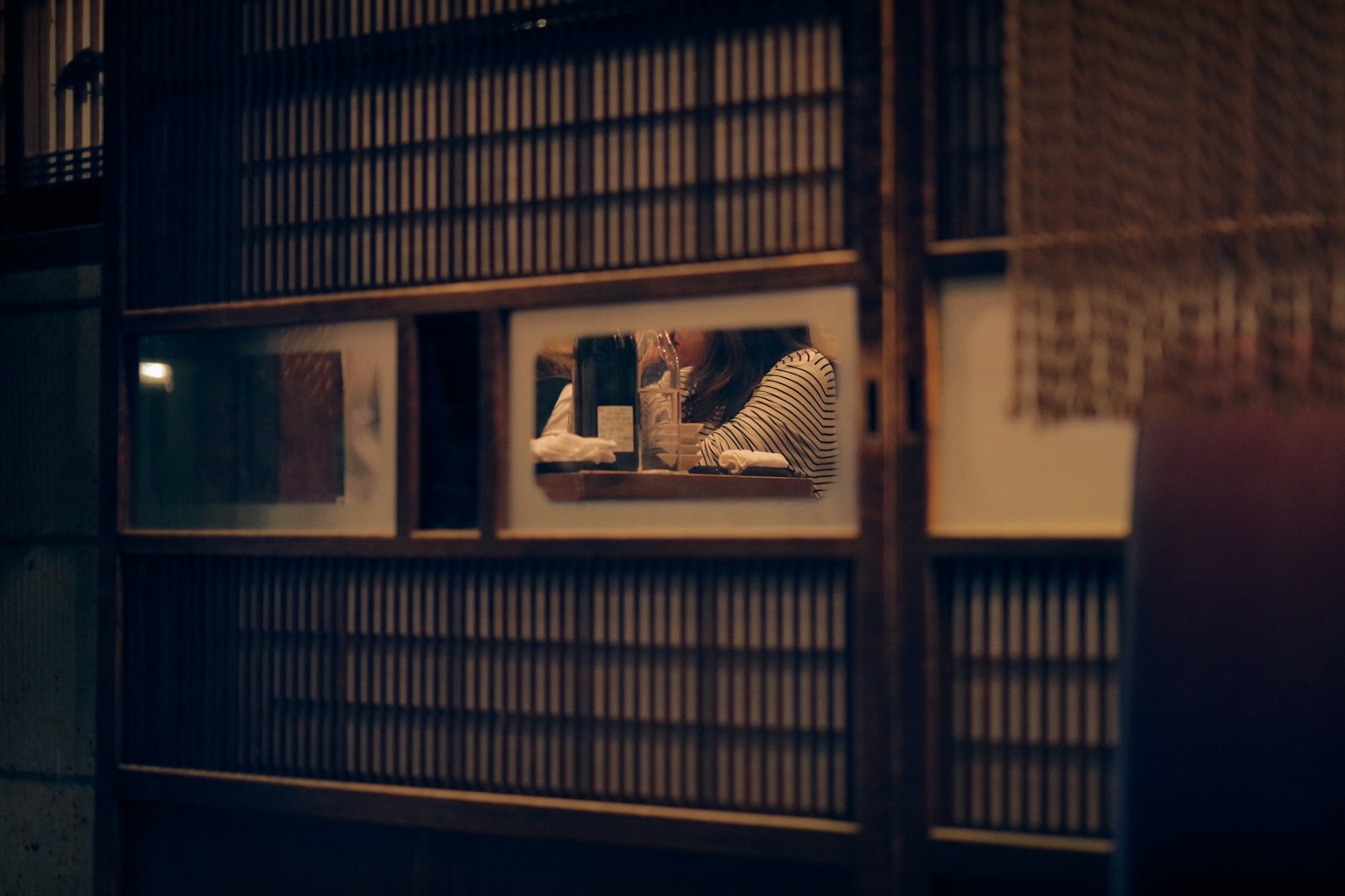 昏暗的房間裡,木製滑動門後可見一個人