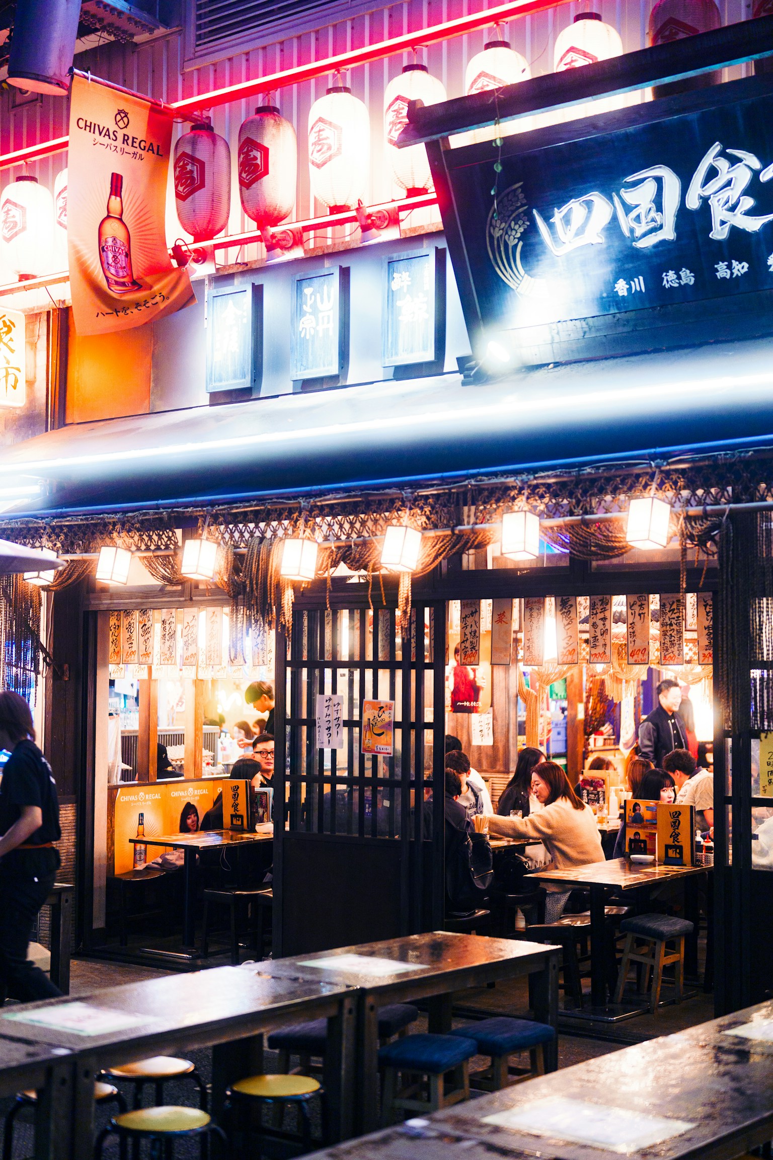 Lively nighttime restaurant exterior with bright lights and people dining