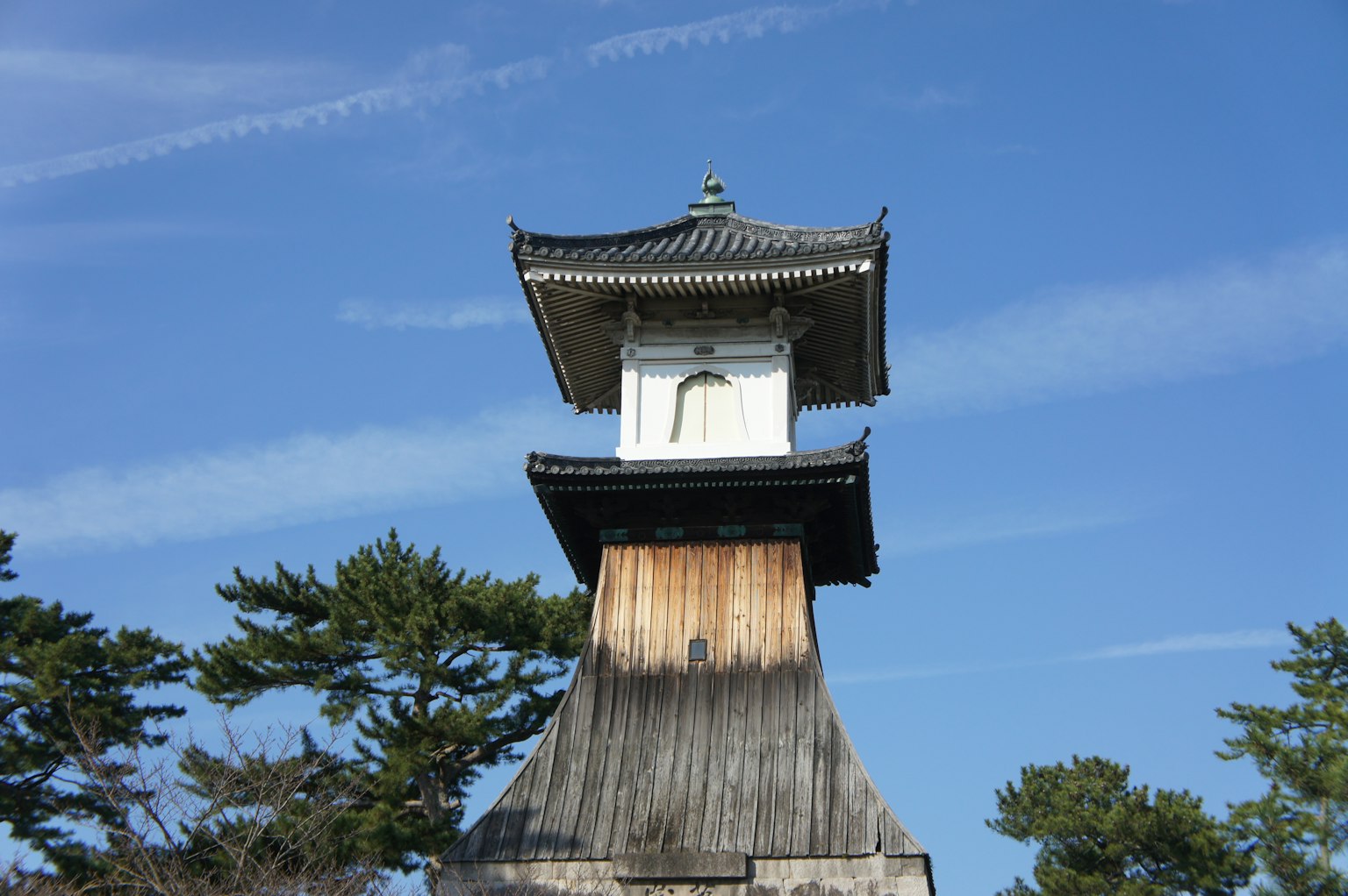 Traditioneller japanischer Uhrturm unter einem blauen Himmel