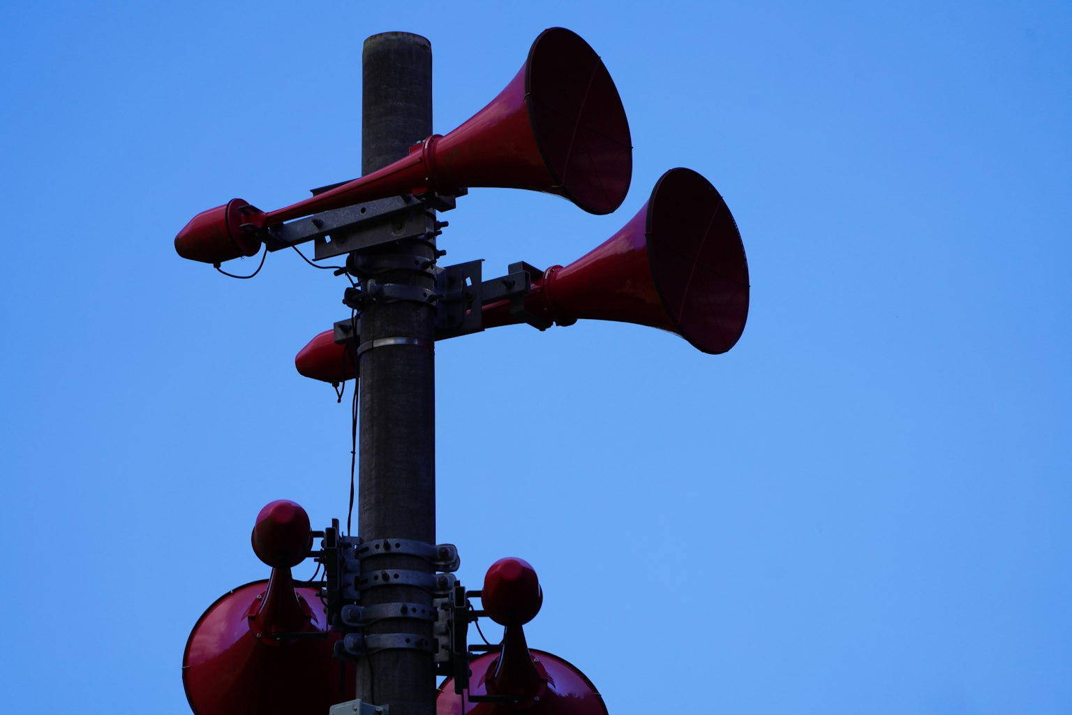 Speaker corong merah yang dipasang di tiang dengan latar belakang langit biru