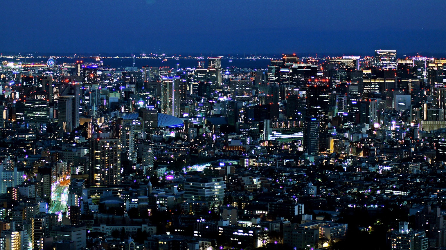 Pemandangan panorama Tokyo di malam hari dengan gedung pencakar langit dan lampu terang