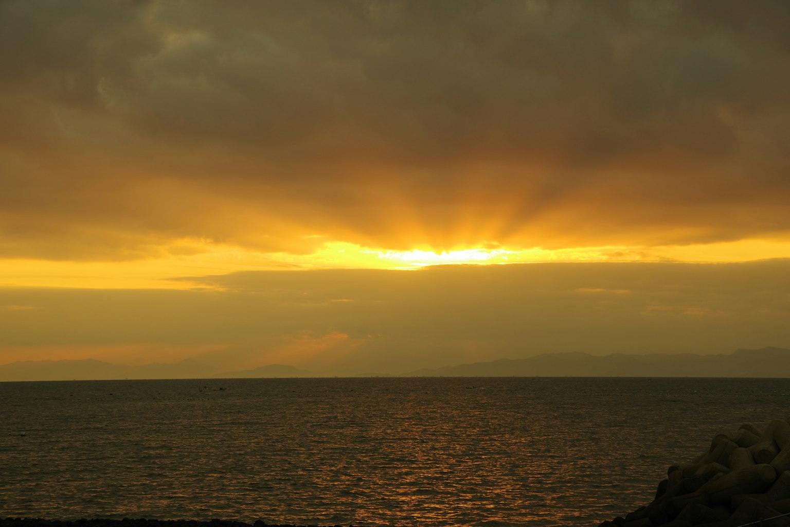 Sonnenuntergang über dem Ozean mit strahlendem Licht und dramatischen Wolken