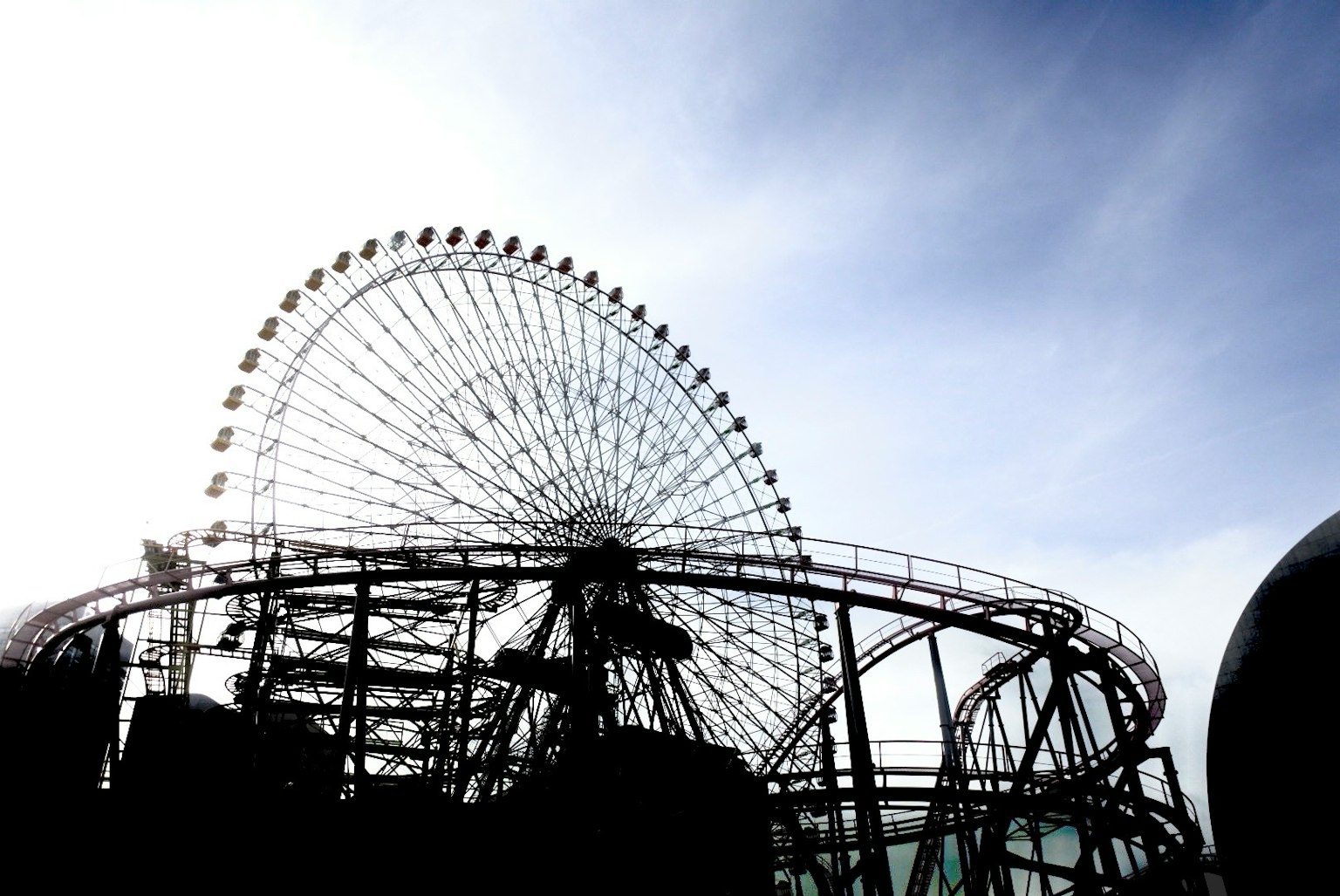 Silhouette of a Ferris wheel against a blue sky