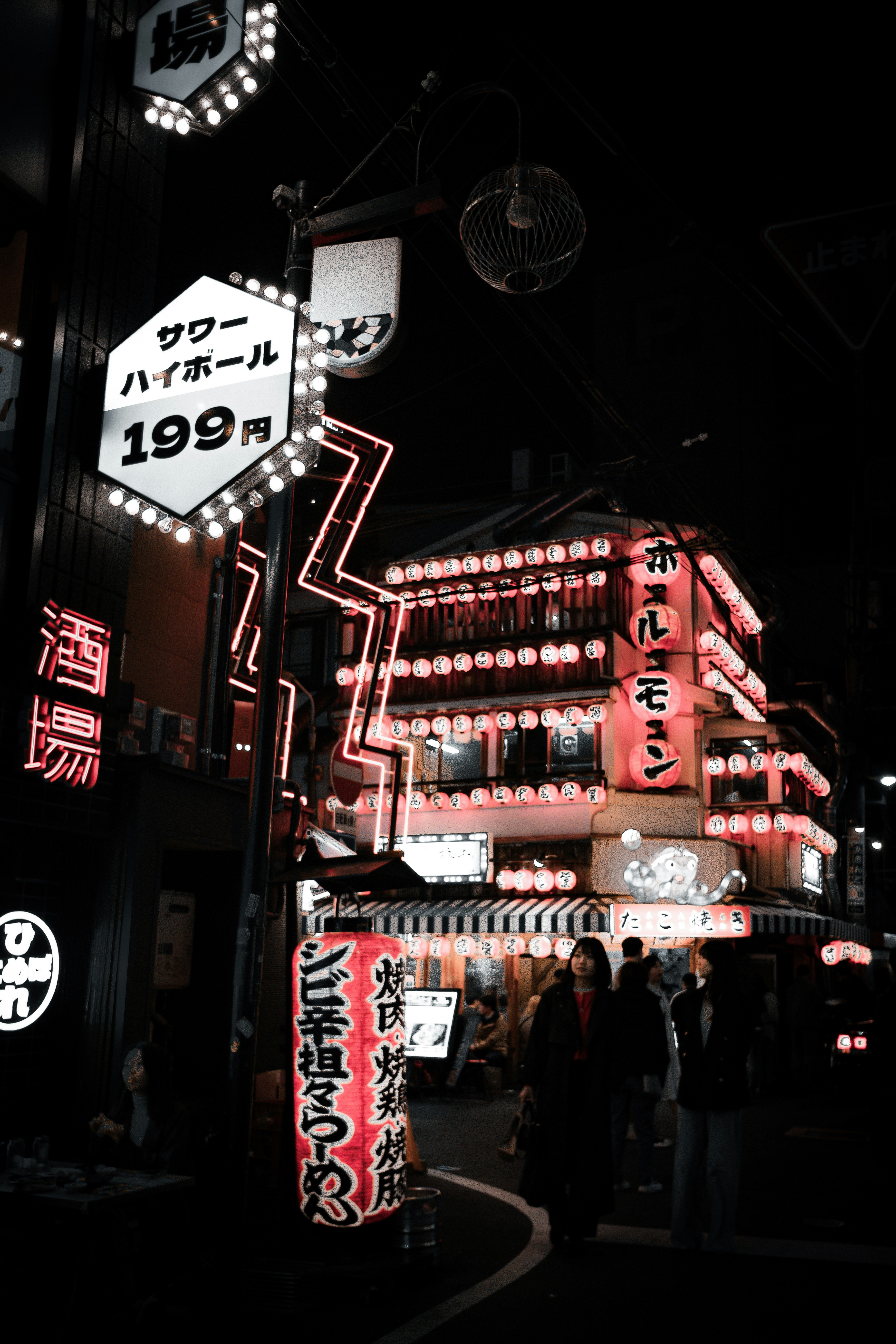 夜のネオンが並ぶ大阪の飲食街の看板と人影
