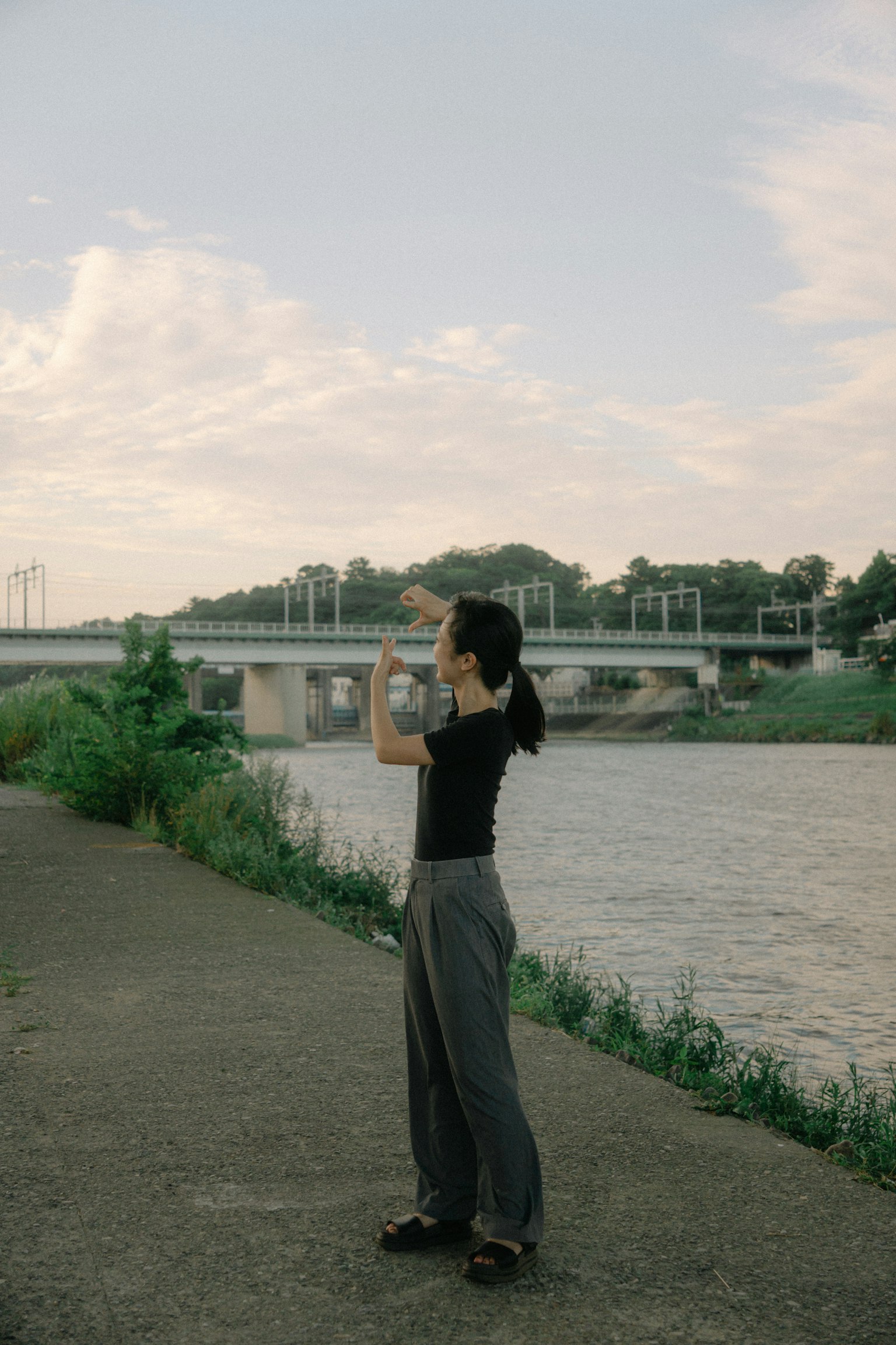 Femme prenant des photos au bord de la rivière avec un pont en arrière-plan