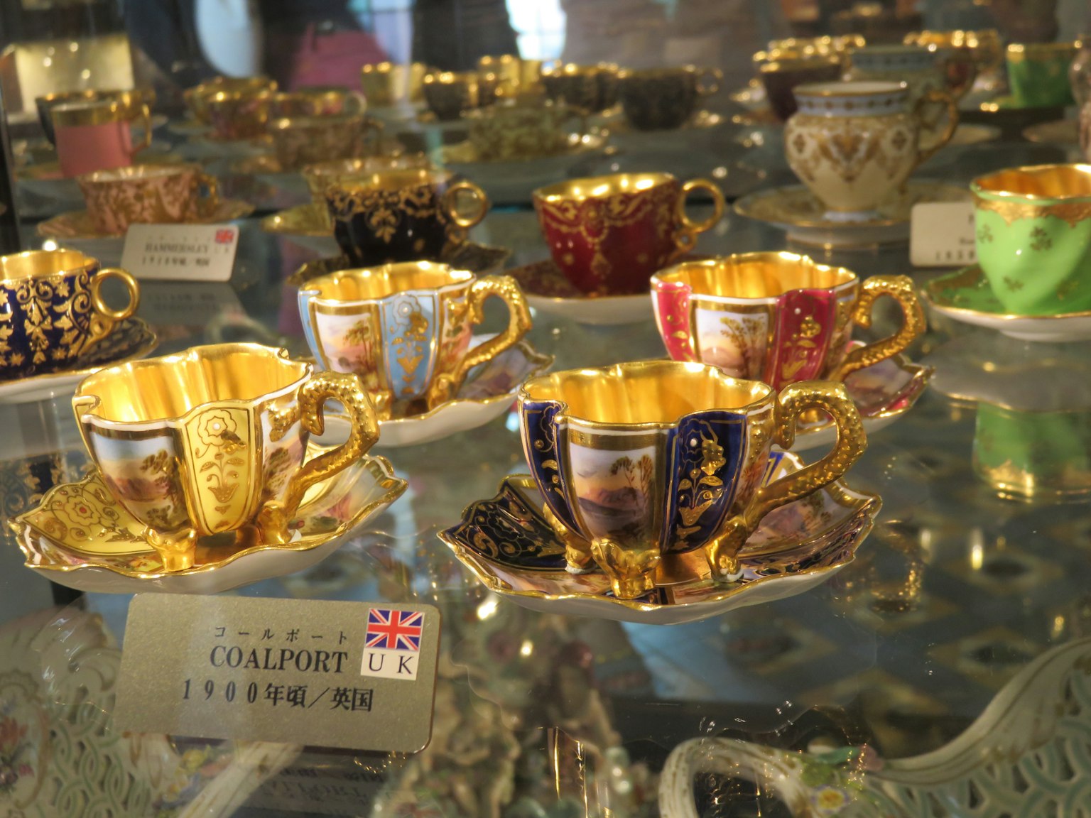 Ein Set aus verzierten Teetassen und Untertassen mit goldenen Details in der Ausstellung