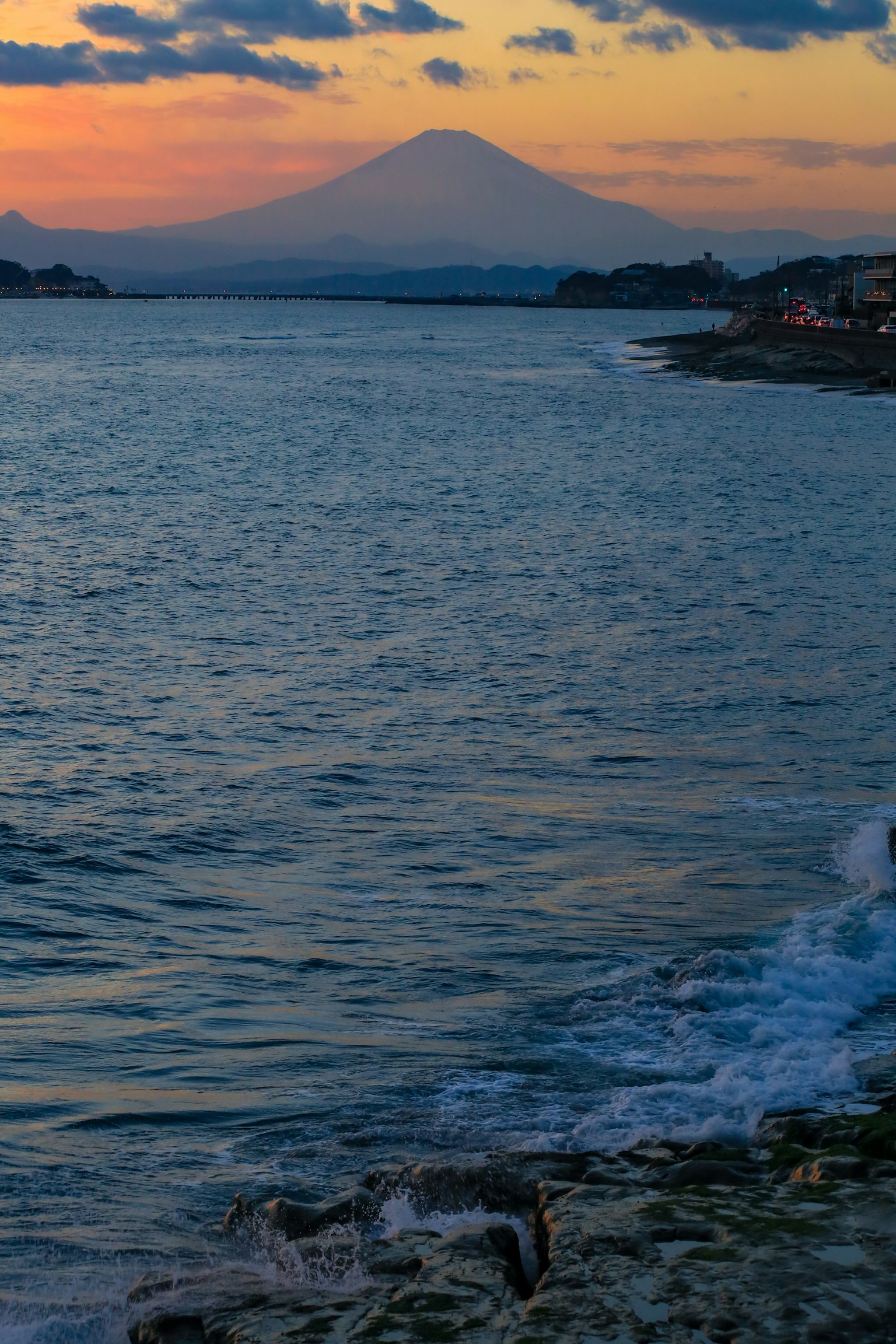 Una hermosa vista del atardecer con el monte Fuji visible al otro lado del mar