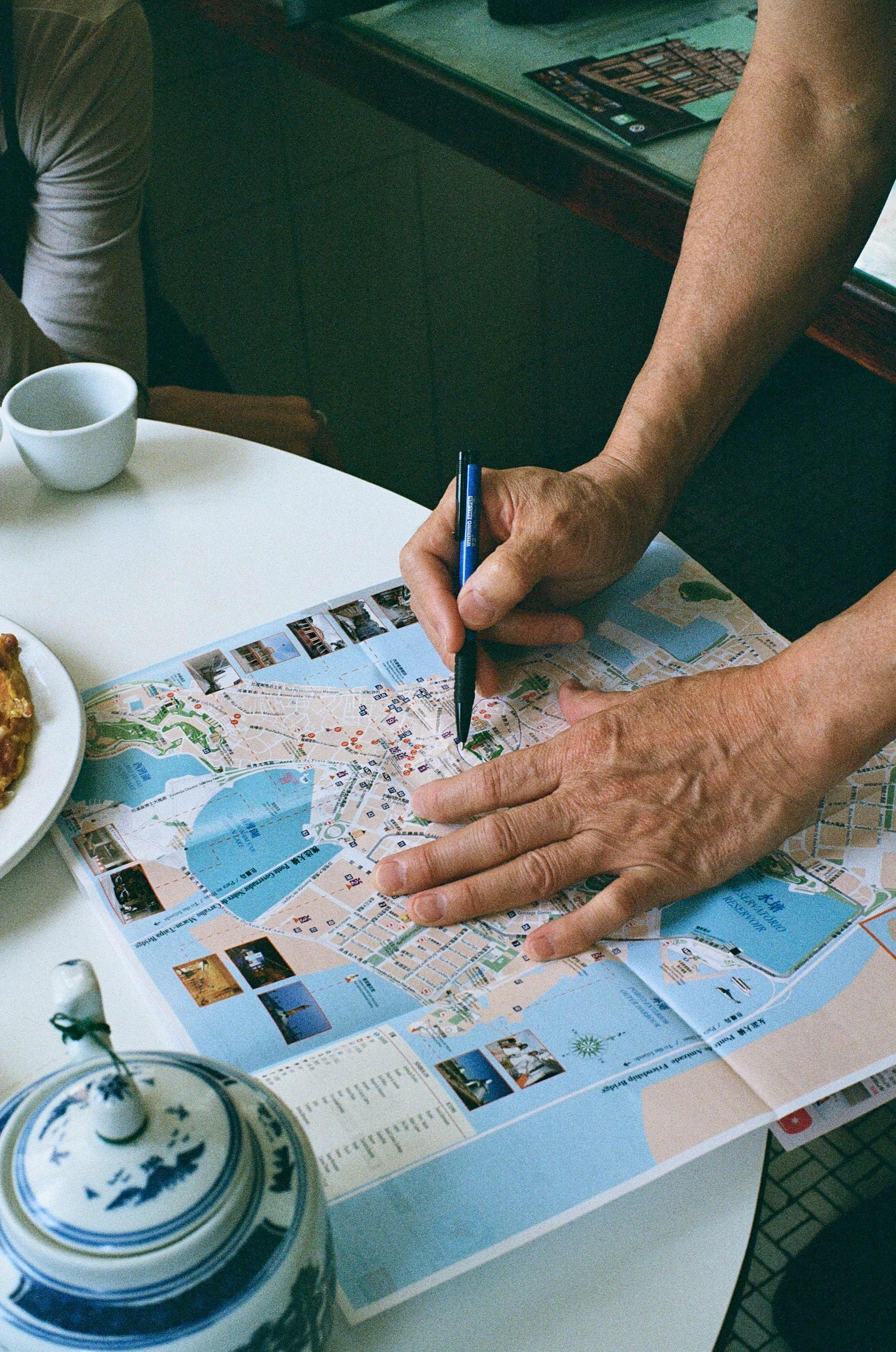 地図に書き込む手と親切な会話のある飲茶店のテーブル