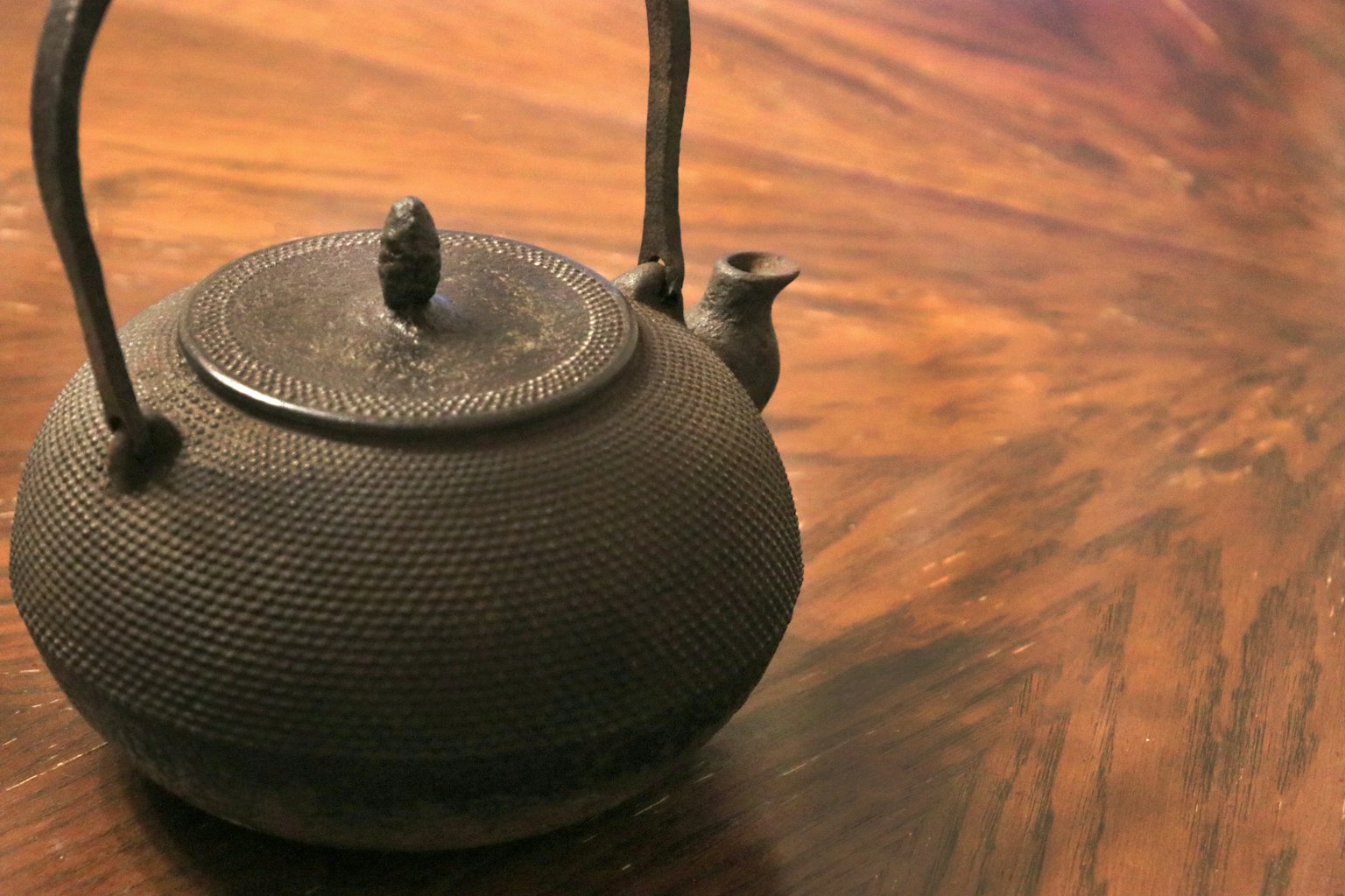 A black iron teapot placed on a wooden table